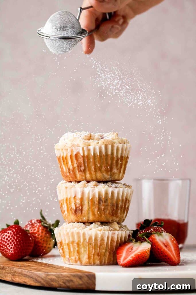 A stack of golden brown strawberry muffins, each featuring a delicious streusel topping and ready to be enjoyed.