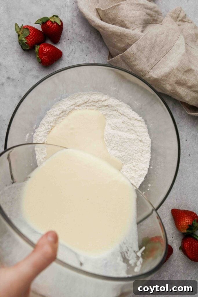 The wet and dry ingredients are gently combined in a bowl to form a thick muffin batter.