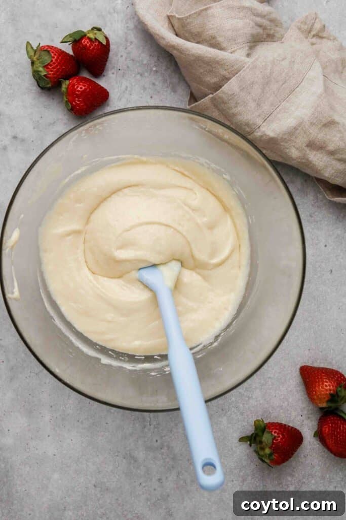 Muffin batter being mixed, showing a thick consistency before adding fruit.