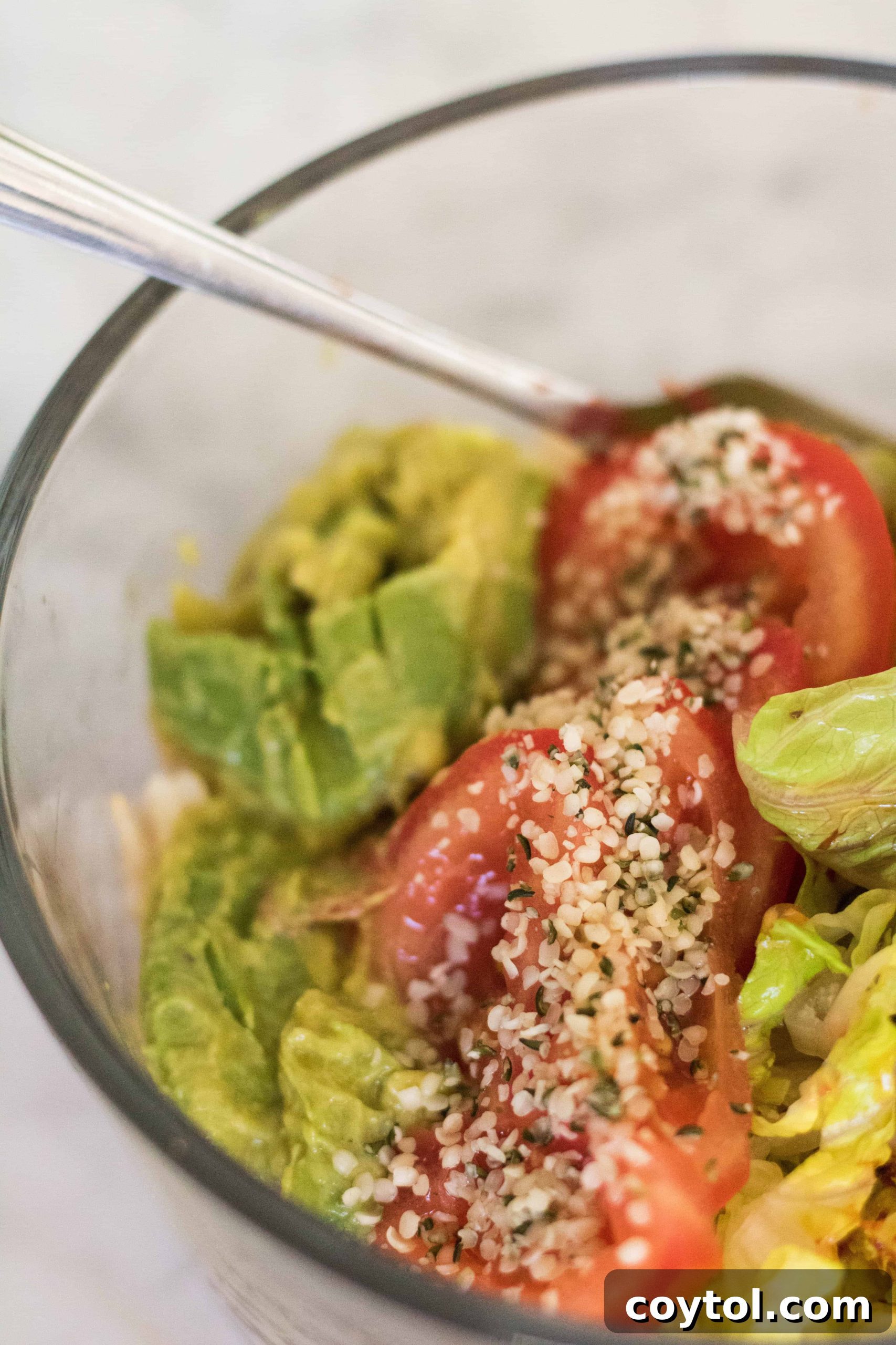 Close-up of a fully assembled gut-healing Buddha bowl, showcasing colorful layers of brown rice, lettuce, avocado, tomato, and kimchi.