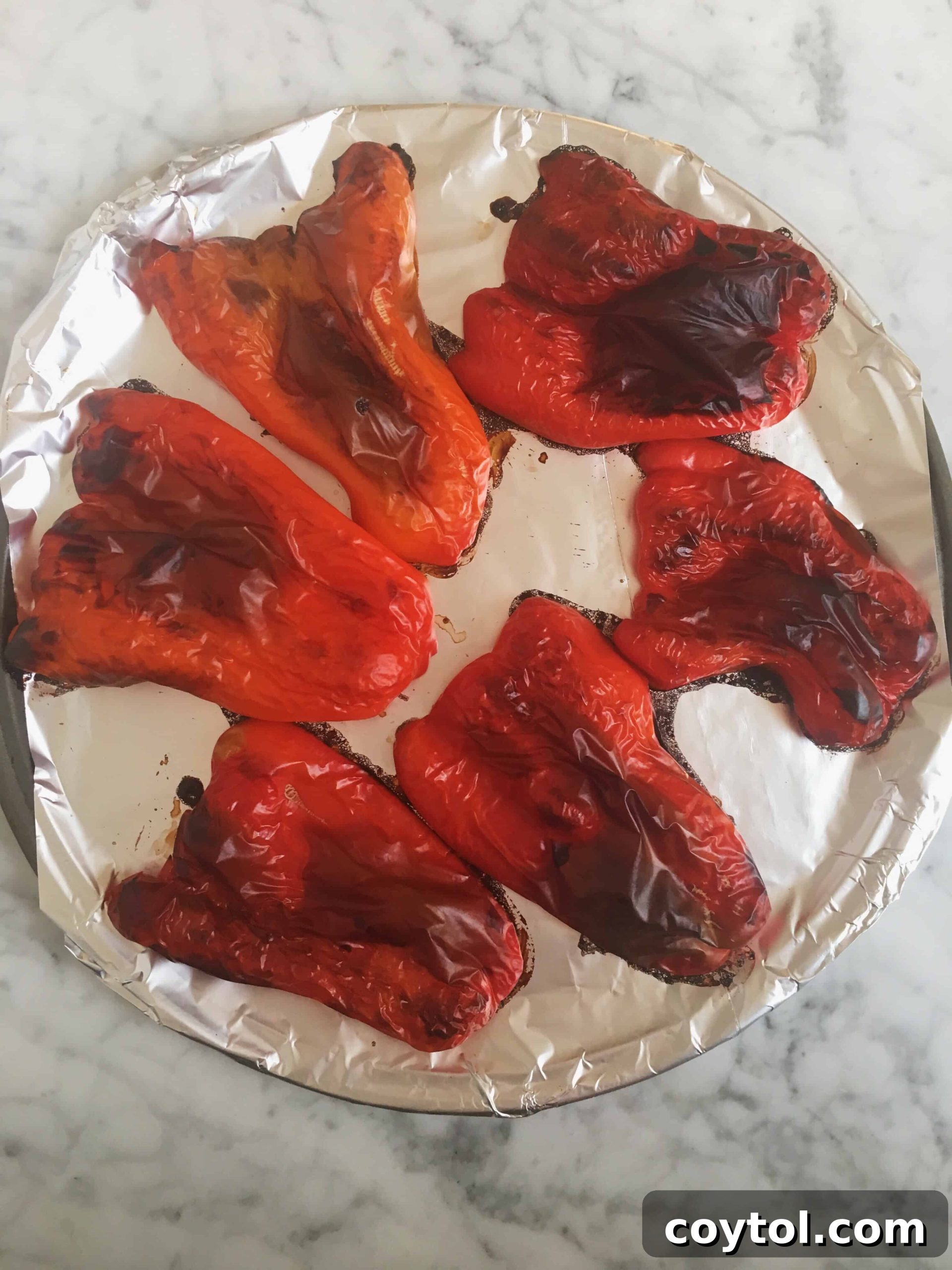 Roasted bell peppers on a baking sheet, showing charred and wrinkled skin