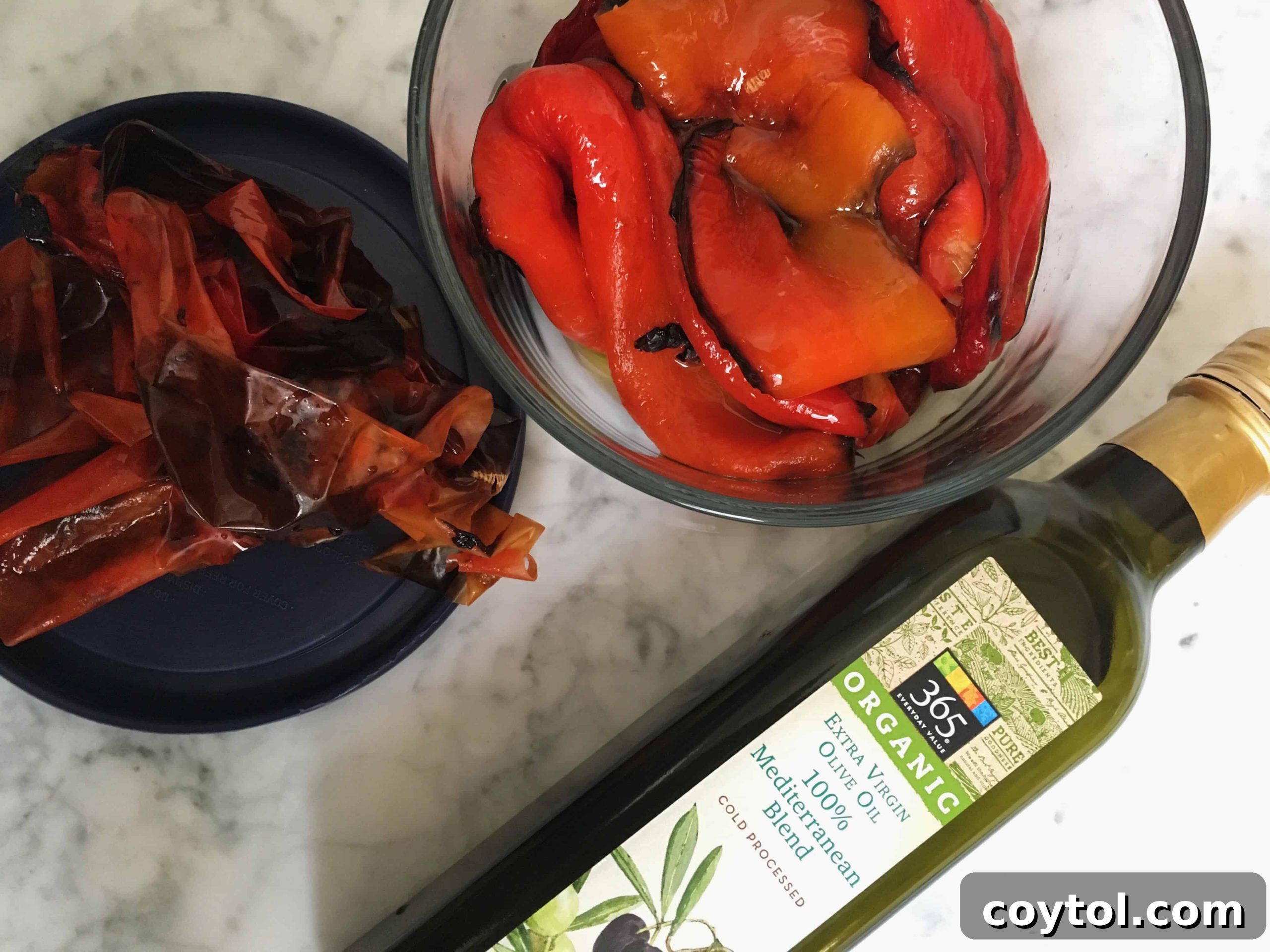 Oven roasted red bell pepper halves in a bowl, covered with a lid to steam