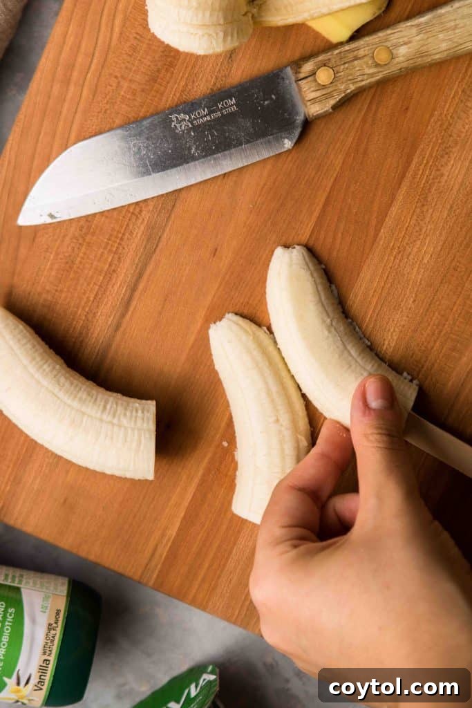 Step-by-step image showing mini chocolate chips being placed on yogurt-covered bananas to create ghost faces for Boonanas.