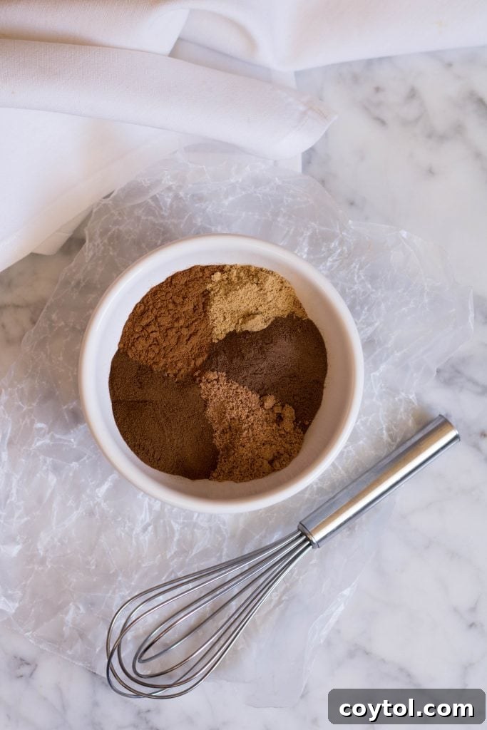 Homemade Pumpkin Pie Spice in a small jar, surrounded by whole spices like cinnamon sticks, star anise, and cloves, evoking a cozy fall atmosphere.