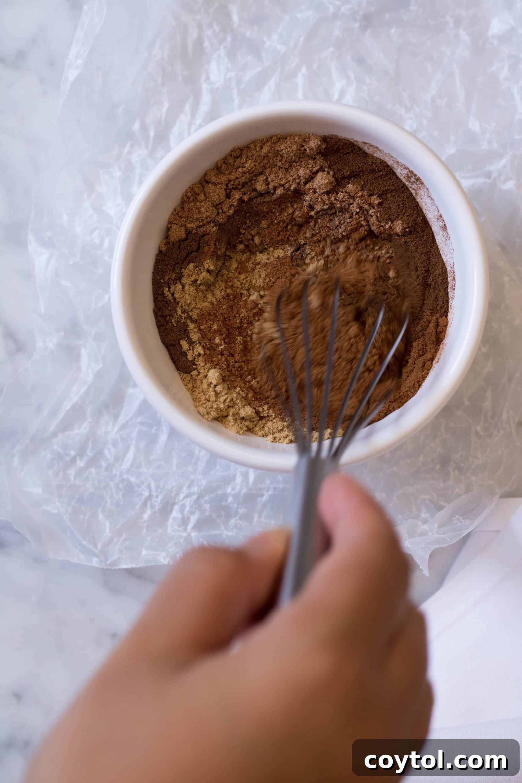 Close-up shot of a bowl filled with pumpkin pie spice mix, showcasing its rich brown color and fine texture.