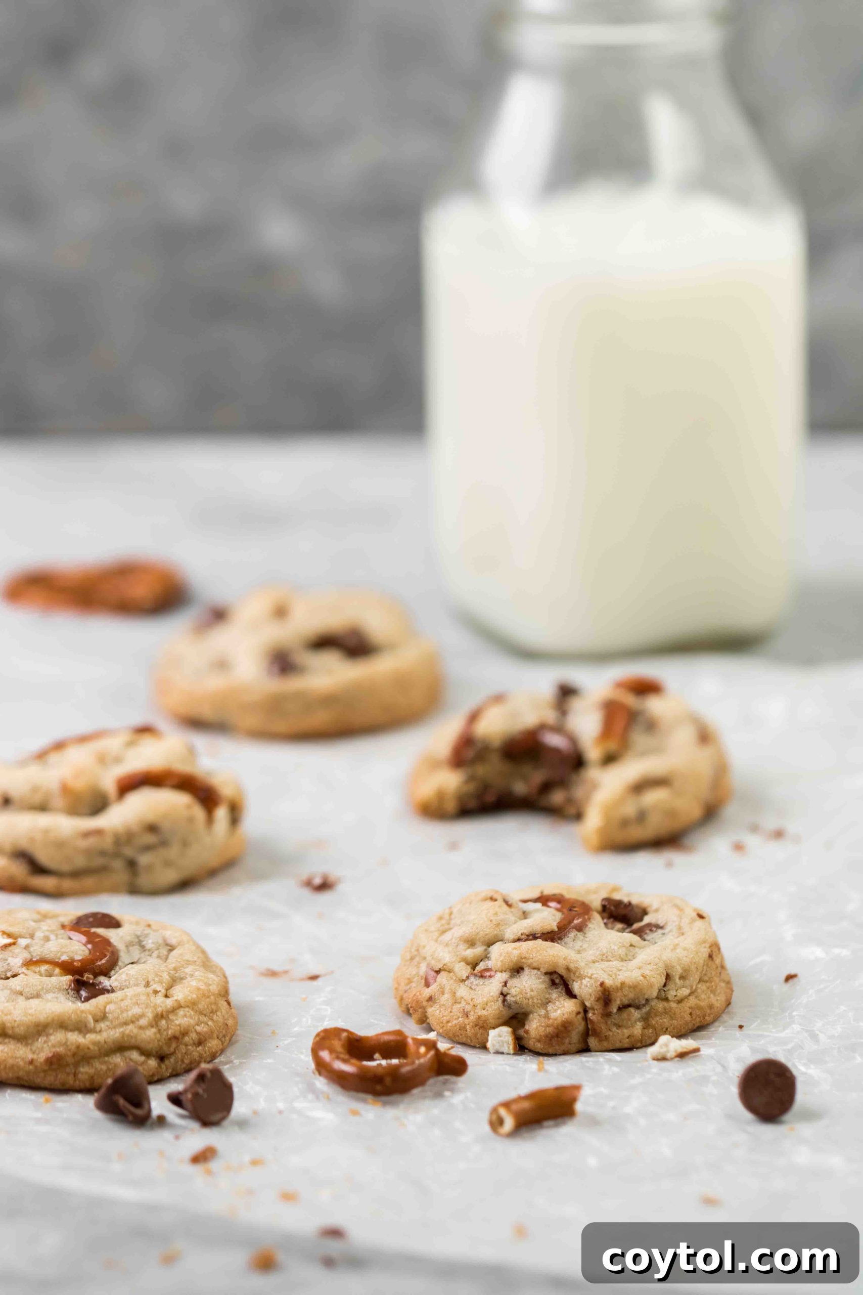 Pretzel chocolate chip cookies with a jug of milk and scattered pretzels