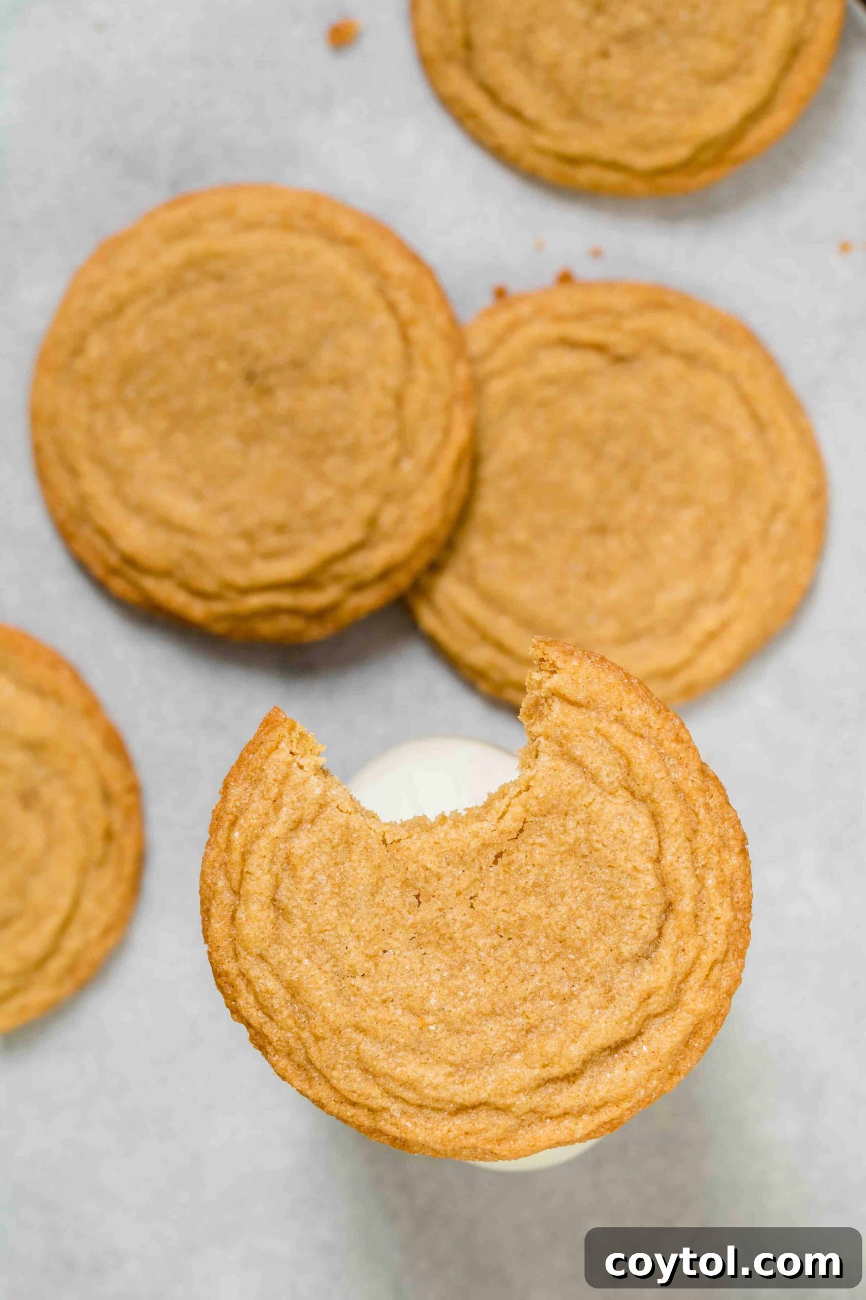 Rich, Chewy Brown Sugar Cookies 4 An overhead shot of golden brown sugar cookies, one with a bite taken out to show its soft interior.