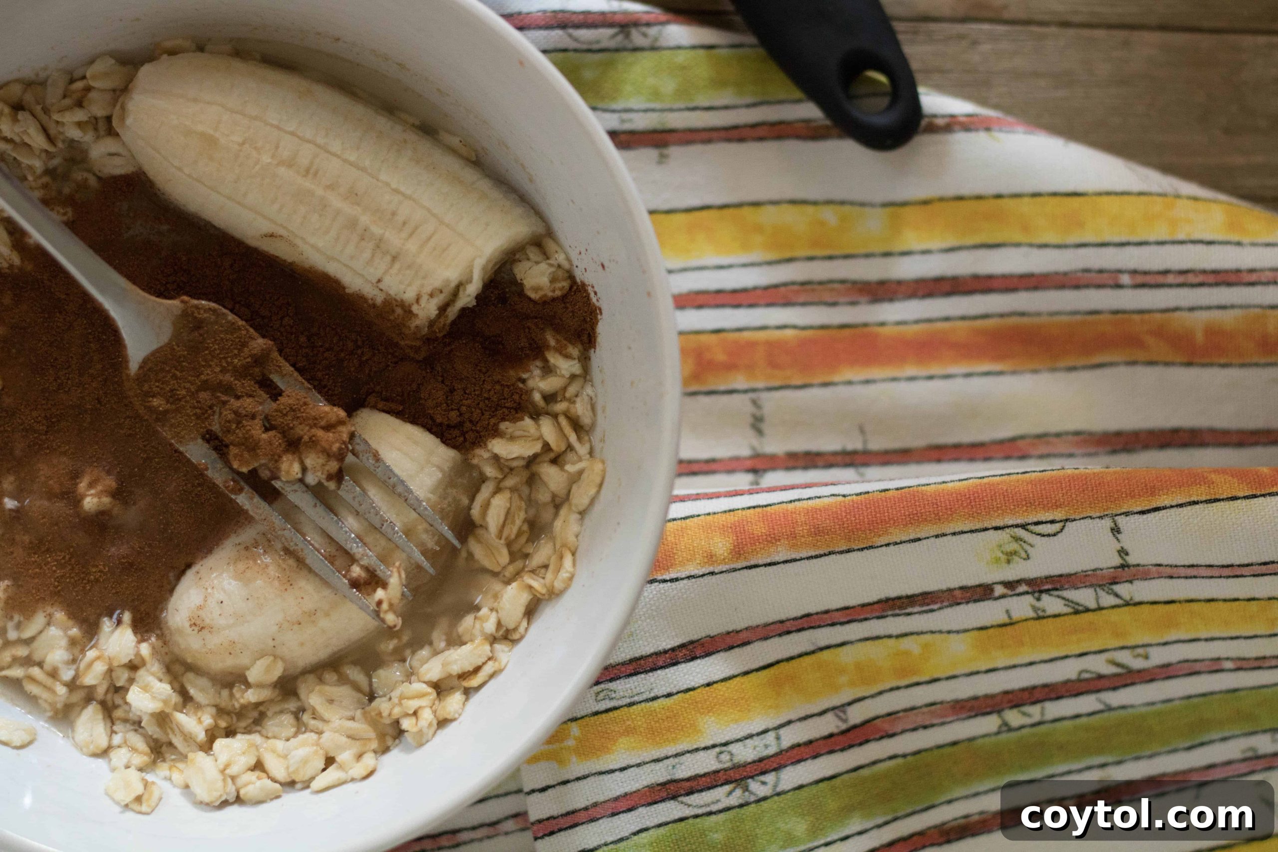 Oats, cinnamon, chia seeds, and milk added to mashed banana in a bowl