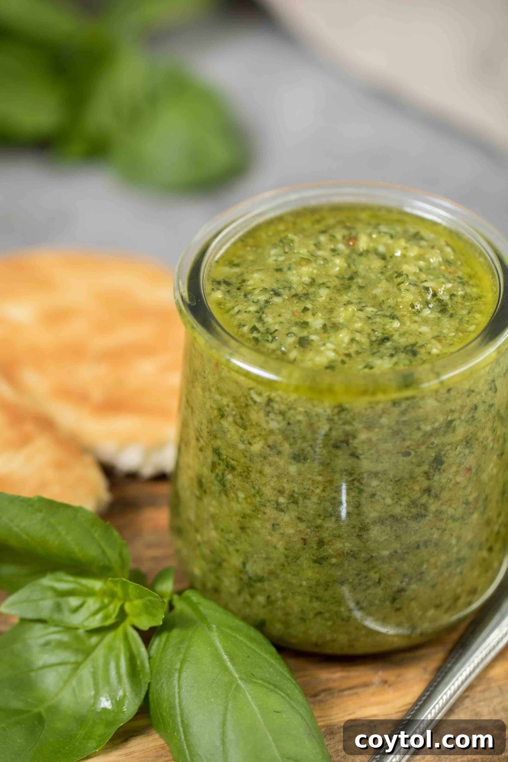 Vibrant green homemade pesto in a rustic bowl, garnished with fresh basil leaves and pine nuts, ready to be served.