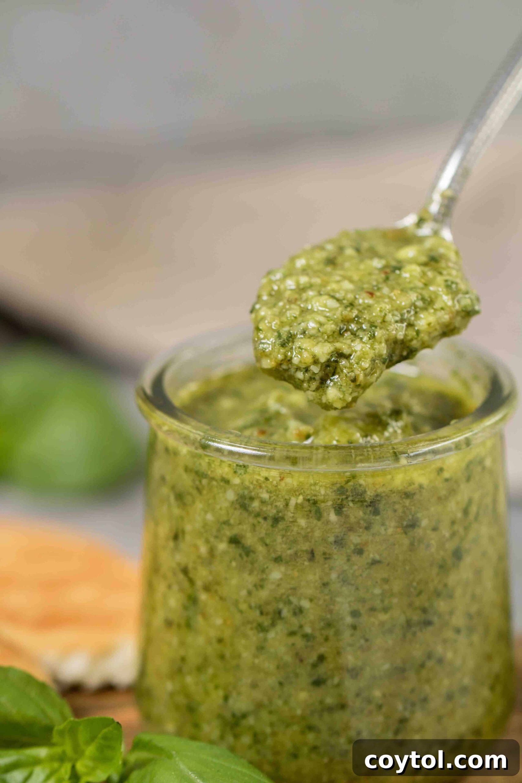 A spoon overflowing with rich, creamy homemade pesto sauce, showcasing its thick texture and vibrant green color.