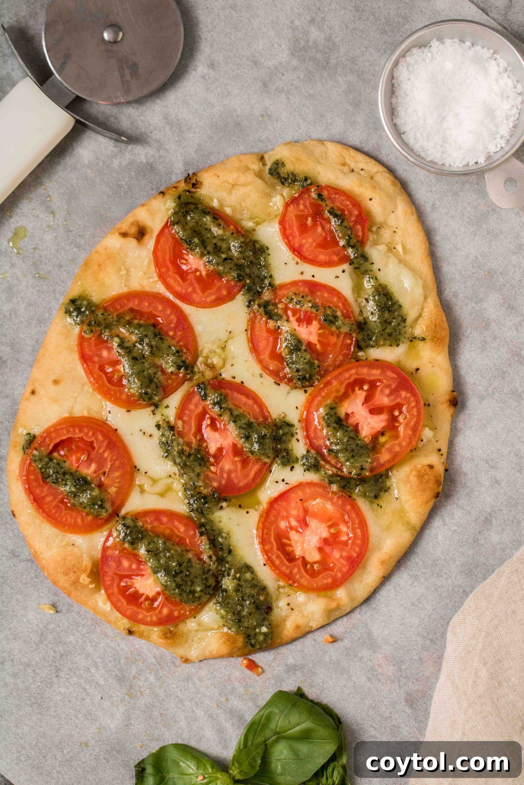 Delicious flatbread pizza with melted mozzarella, fresh tomato slices, and a vibrant pesto drizzle.