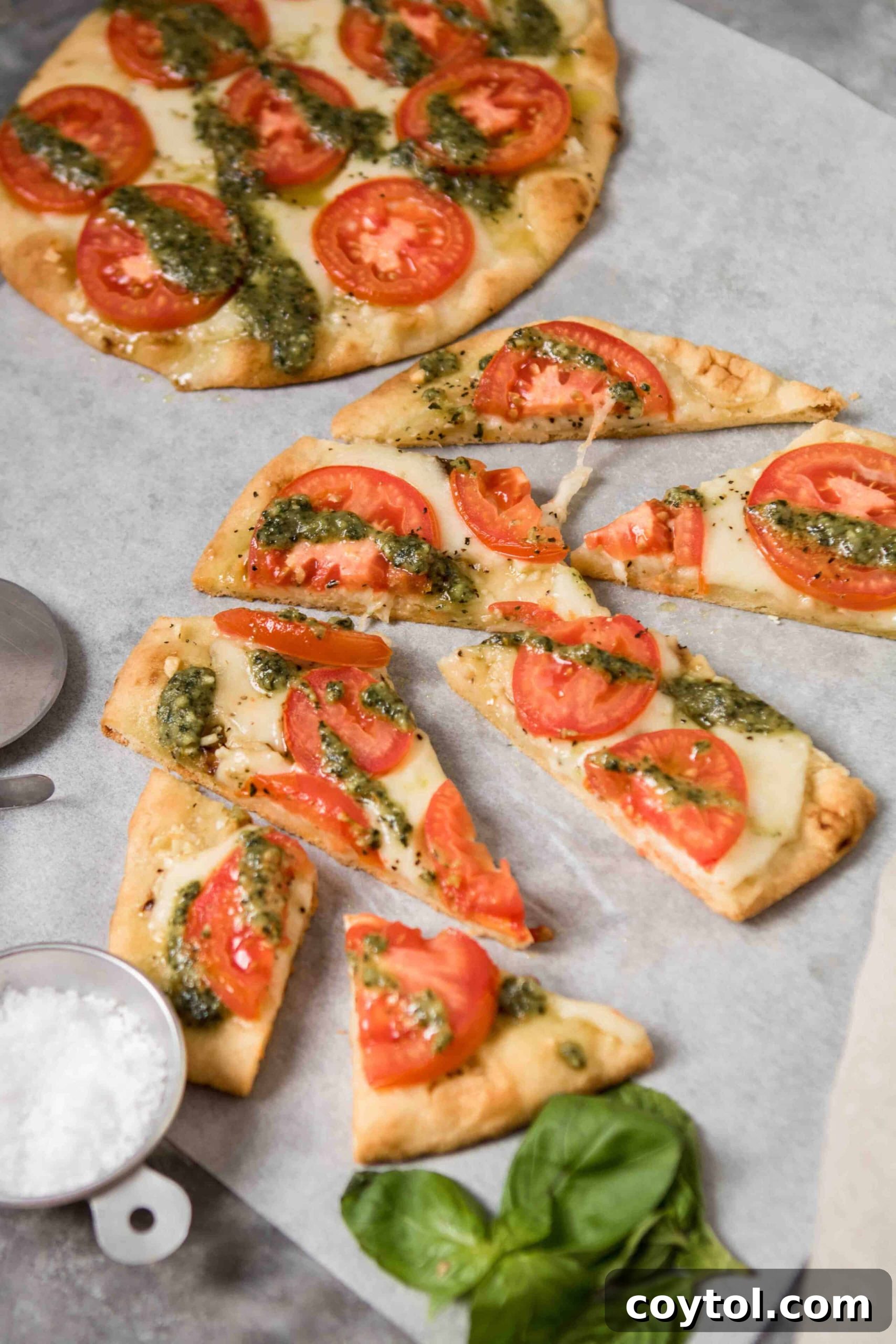 Freshly baked flatbread pizzas, sliced and garnished with sea salt and fresh basil leaves, ready to serve.