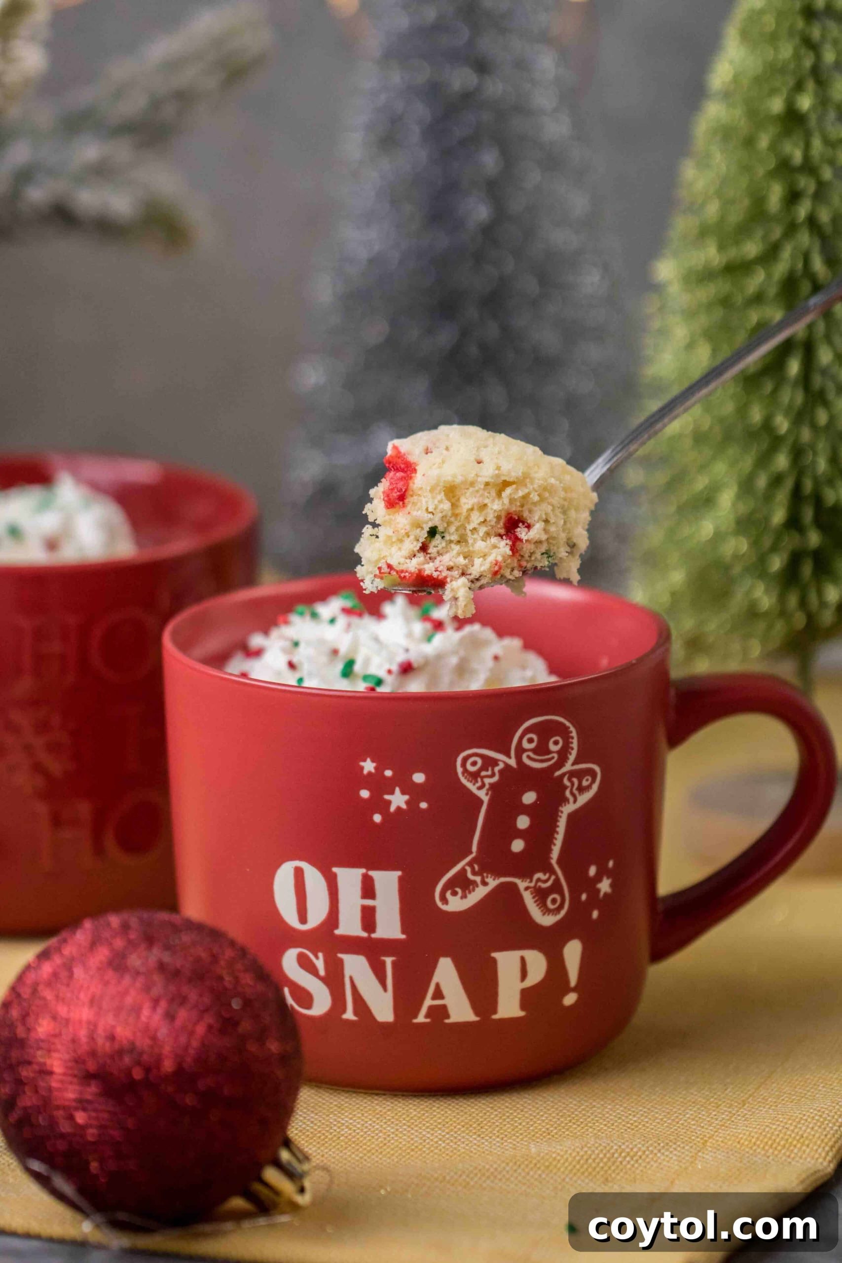 Festive Christmas mug cake adorned with sprinkles, served in a cheerful Christmas mug, ready for a quick holiday treat.