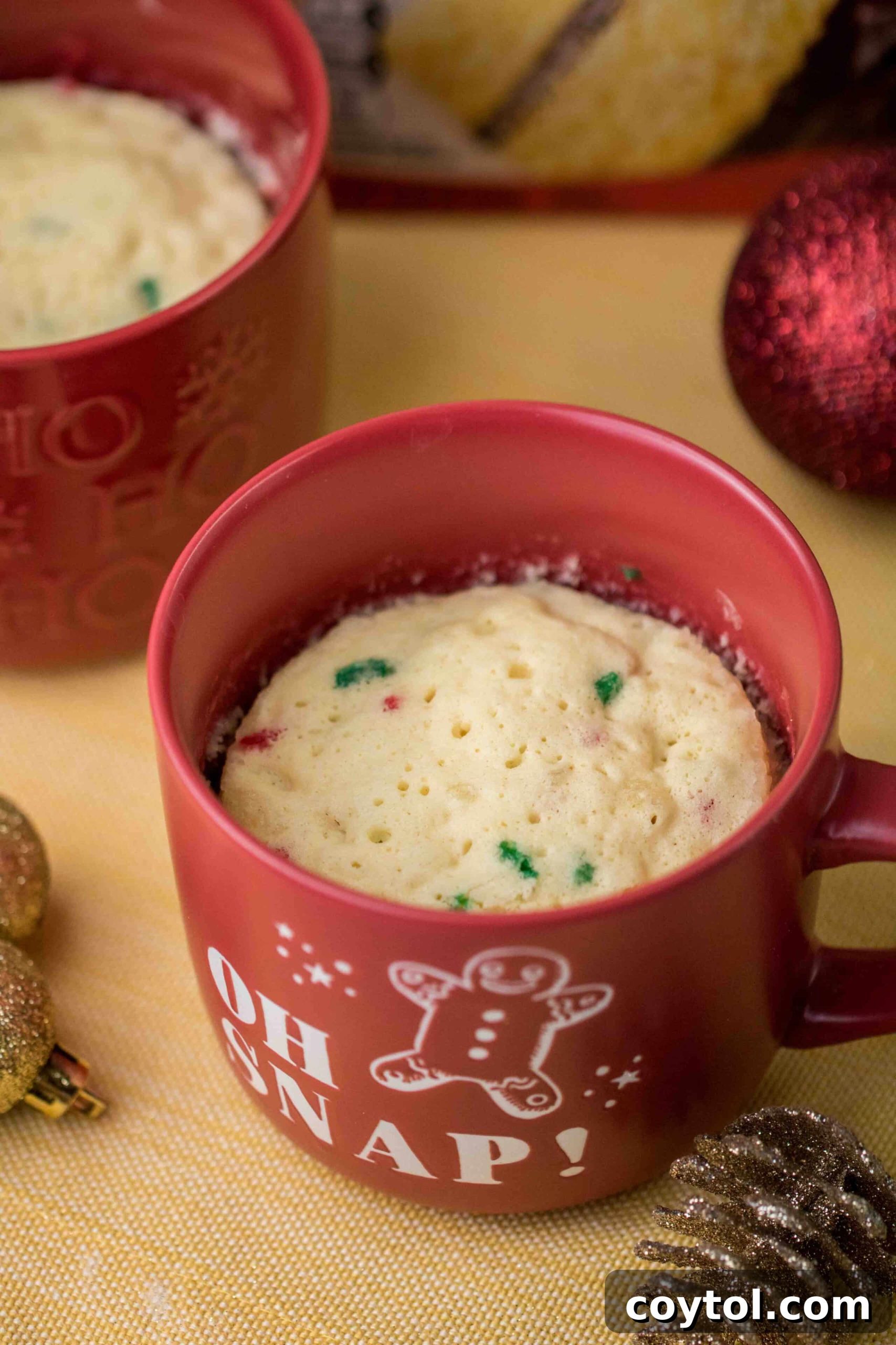Testing a cooked Christmas mug cake for doneness by gently pressing the spongy top.