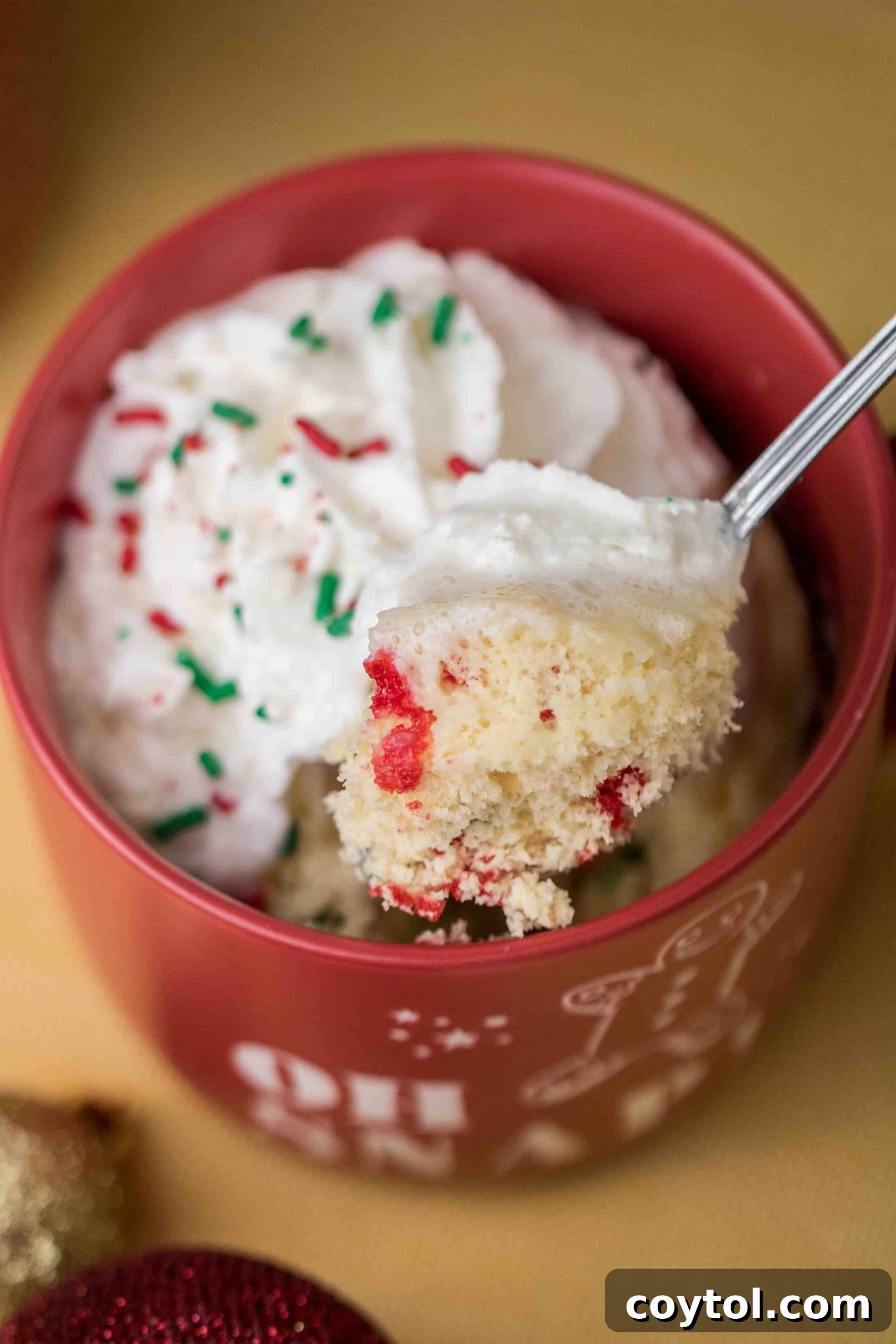Close-up of a fluffy Christmas mug cake interior, studded with colorful festive sprinkles, perfect for a quick holiday treat.
