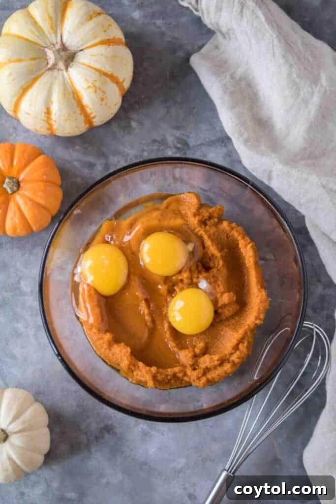 Pumpkin puree and three egg yolks in a glass bowl ready to be whisked together.
