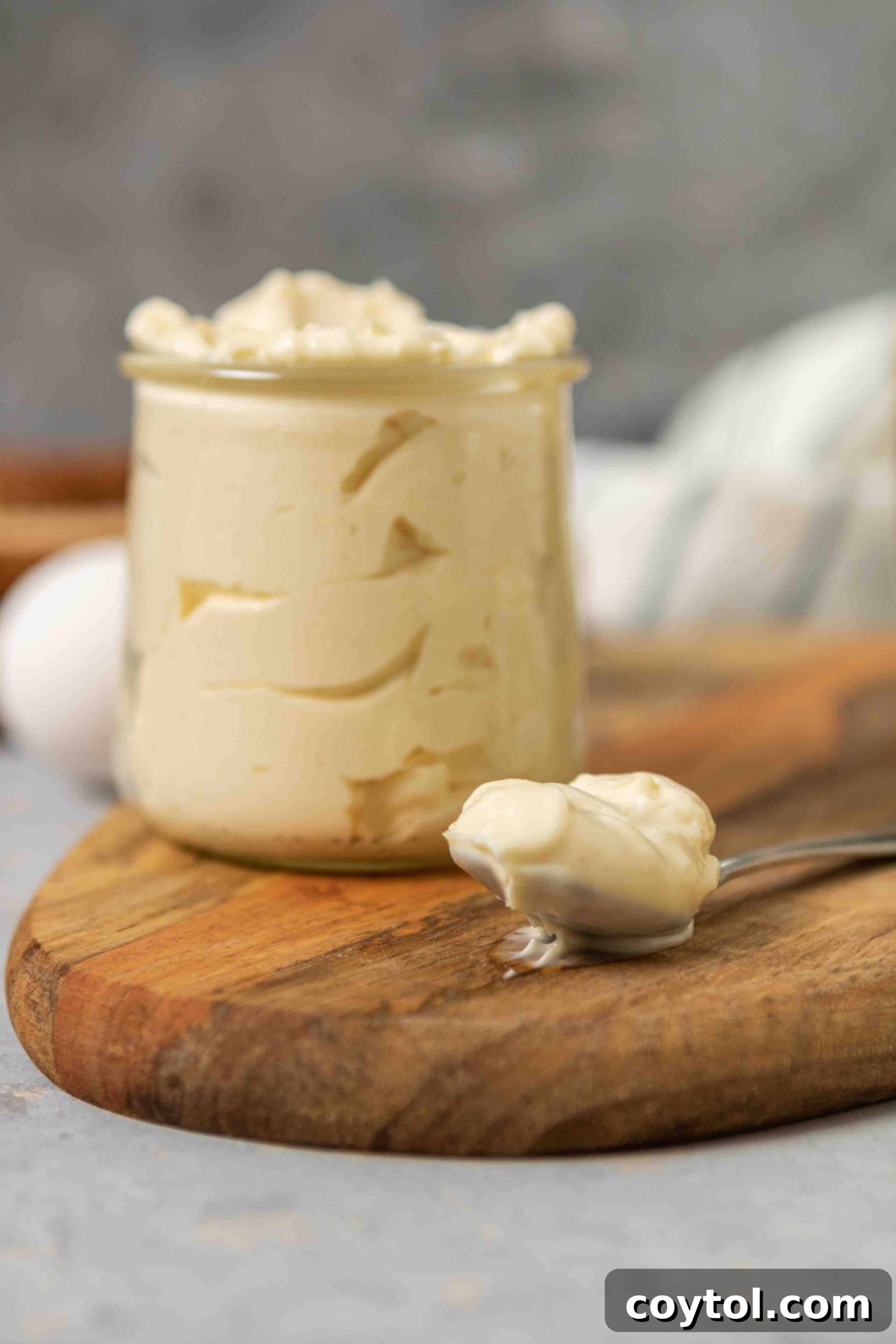 Whip Up Perfect Mayonnaise in Your Food Processor 4 Homemade mayonnaise in a jar with a spoon next to it, showcasing its creamy texture.
