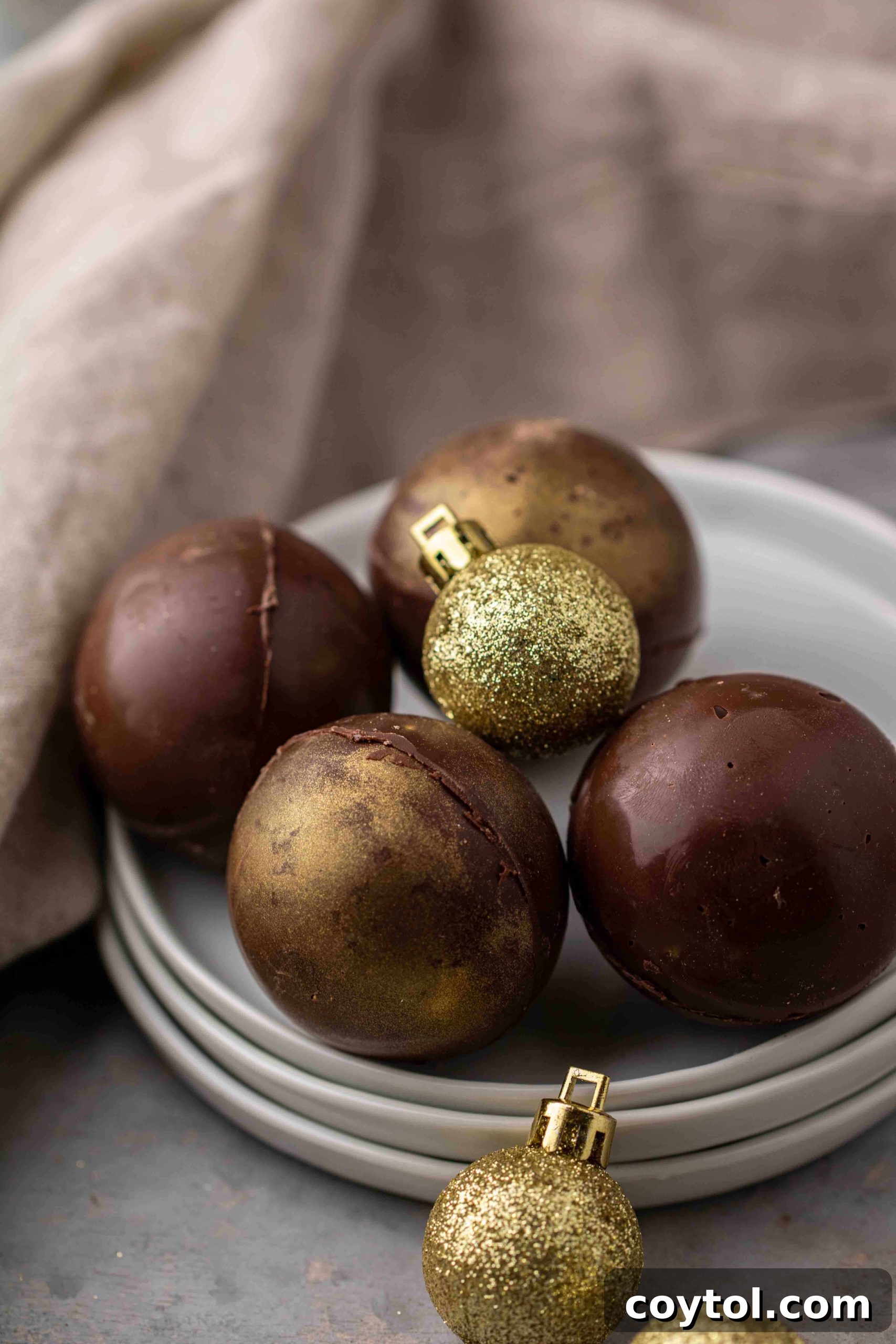 Multiple hot chocolate bombs, some coated in gold dust, on a tray