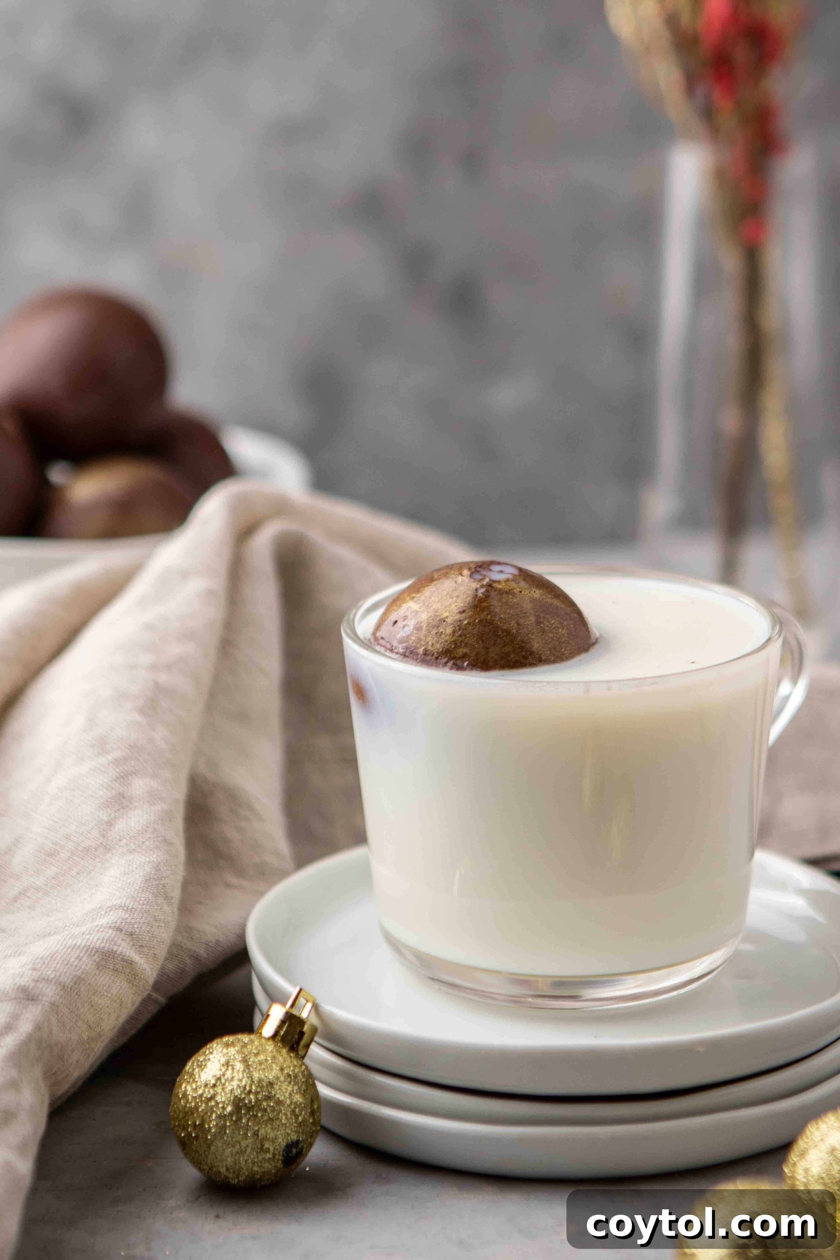 Golden hot chocolate bomb gently melting in a cup of hot milk