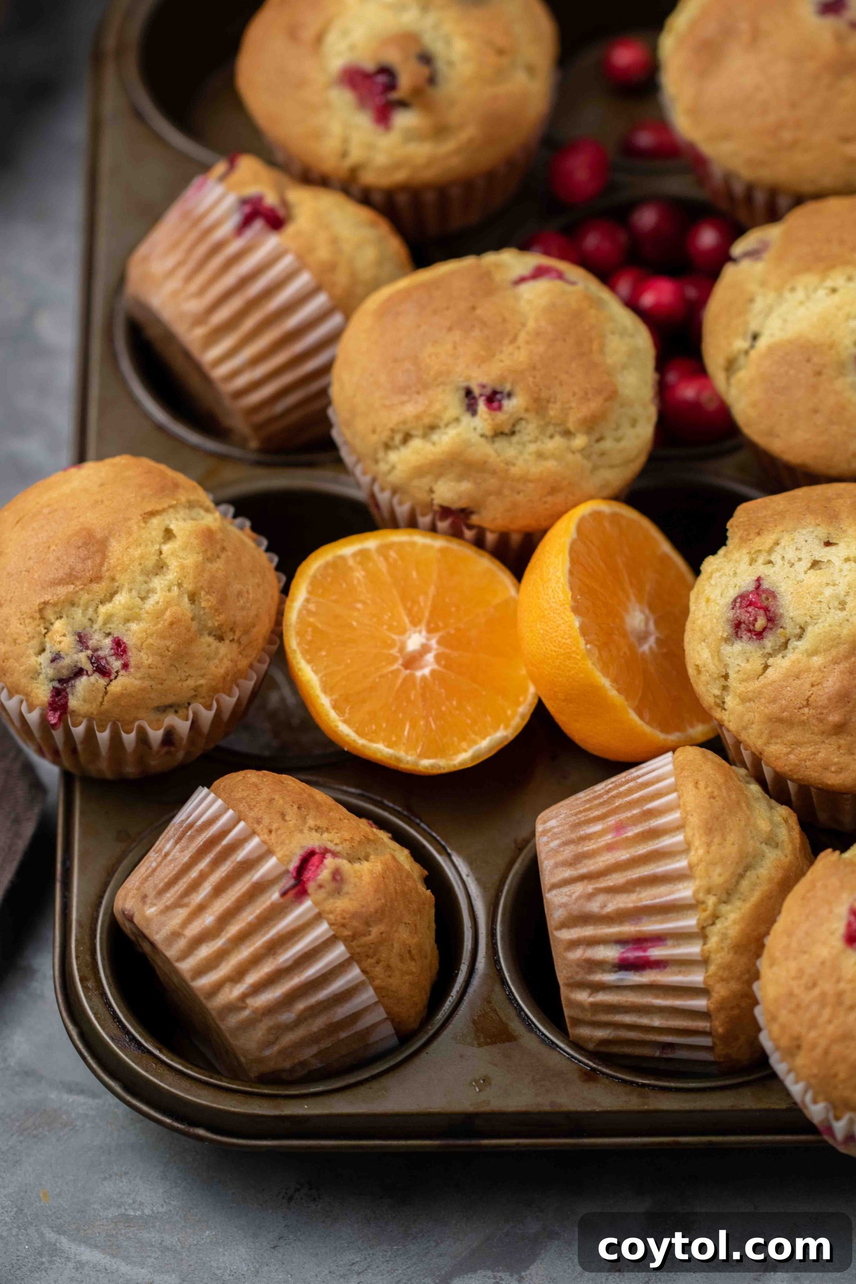 Beautifully glazed cranberry orange muffins arranged on a rustic wooden board.
