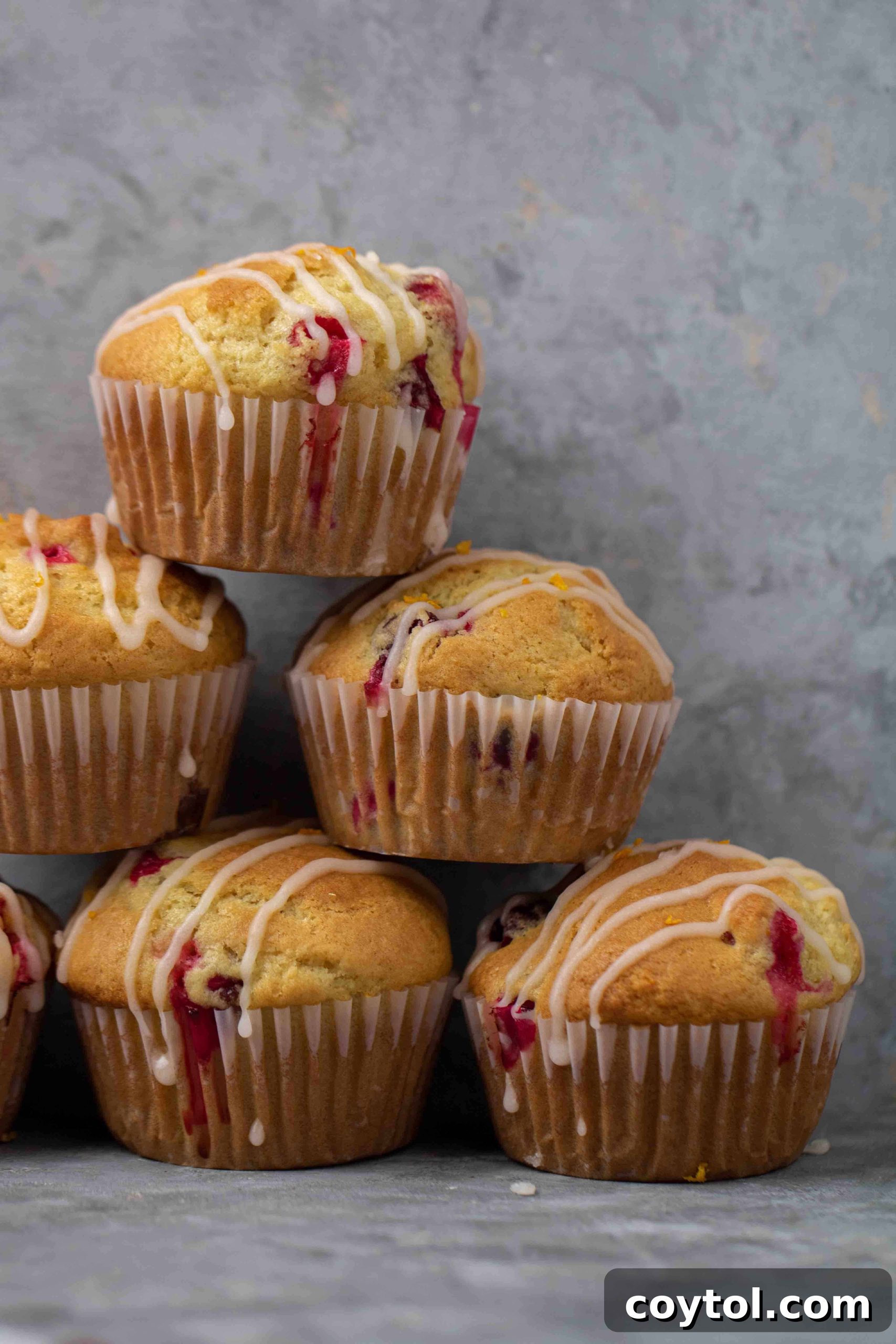 A stack of perfectly baked orange cranberry muffins, showing off their golden-brown tops and vibrant cranberry inclusions.