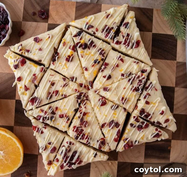 Homemade Cranberry Bliss Bars Surpassing Starbucks 14 Overhead view of frosted cranberry bliss bars cut into triangles and arranged neatly on a wooden board.