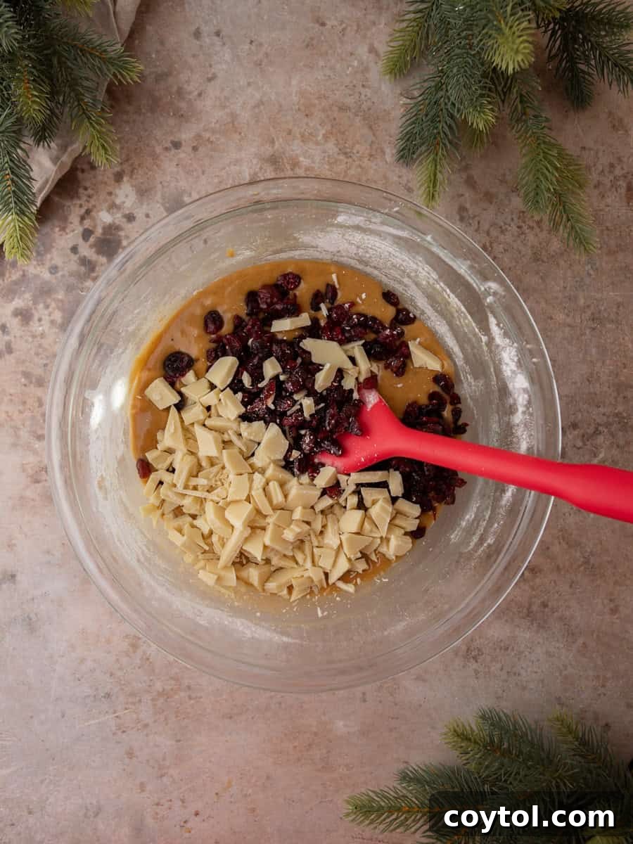 Homemade Cranberry Bliss Bars Surpassing Starbucks 7 Blondie batter mixed with dried cranberries and chopped white chocolate in a glass bowl.