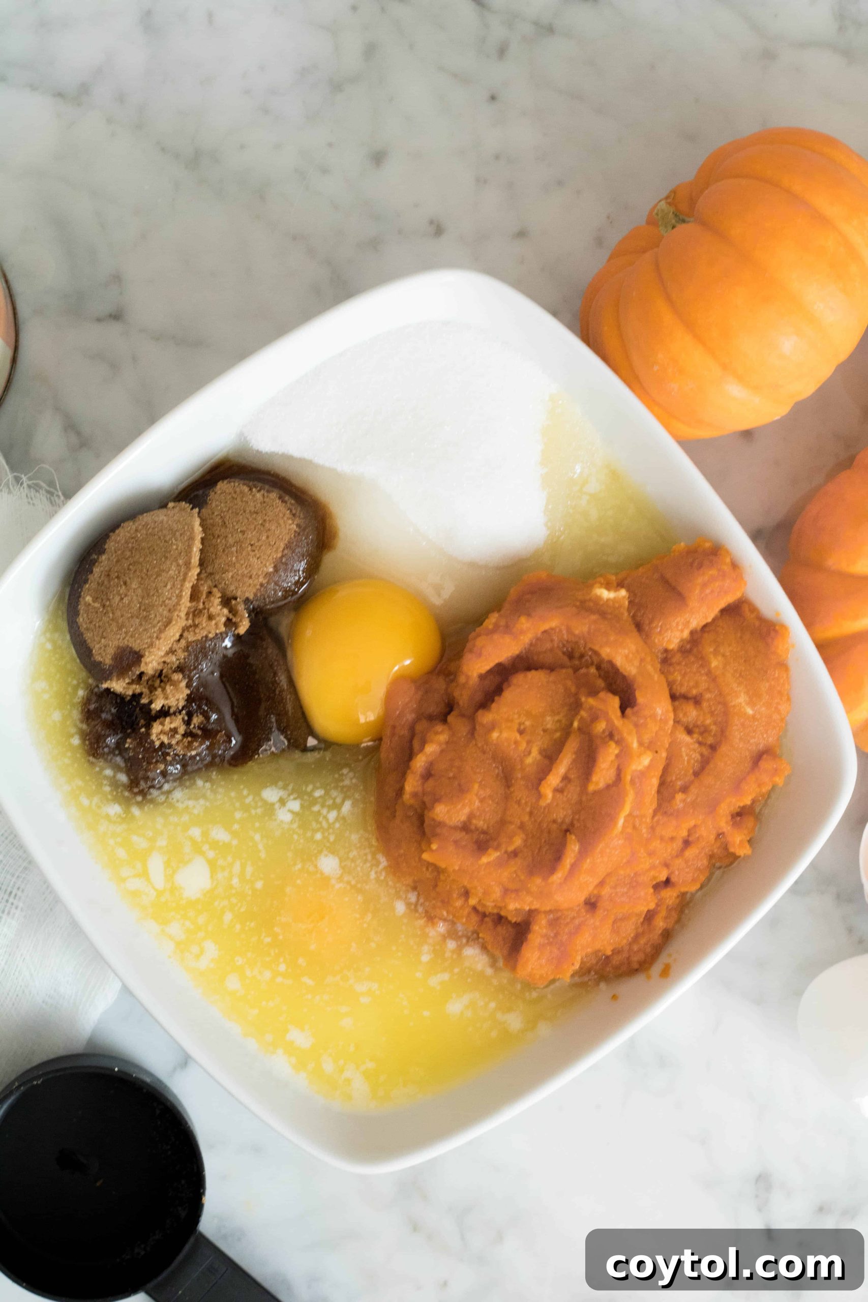 Ingredients for wet mixture including eggs, pumpkin puree, brown sugar, granulated sugar, and melted butter, ready to be combined for the muffin batter.