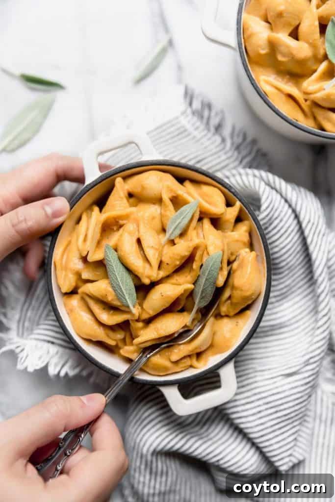 Luxurious vegan pumpkin mac and cheese garnished with fresh sage leaves, a hearty fall dish.