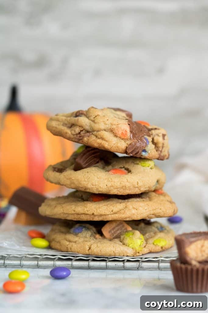 Four golden-brown cookies stacked with colorful Halloween candies on top and in the foreground