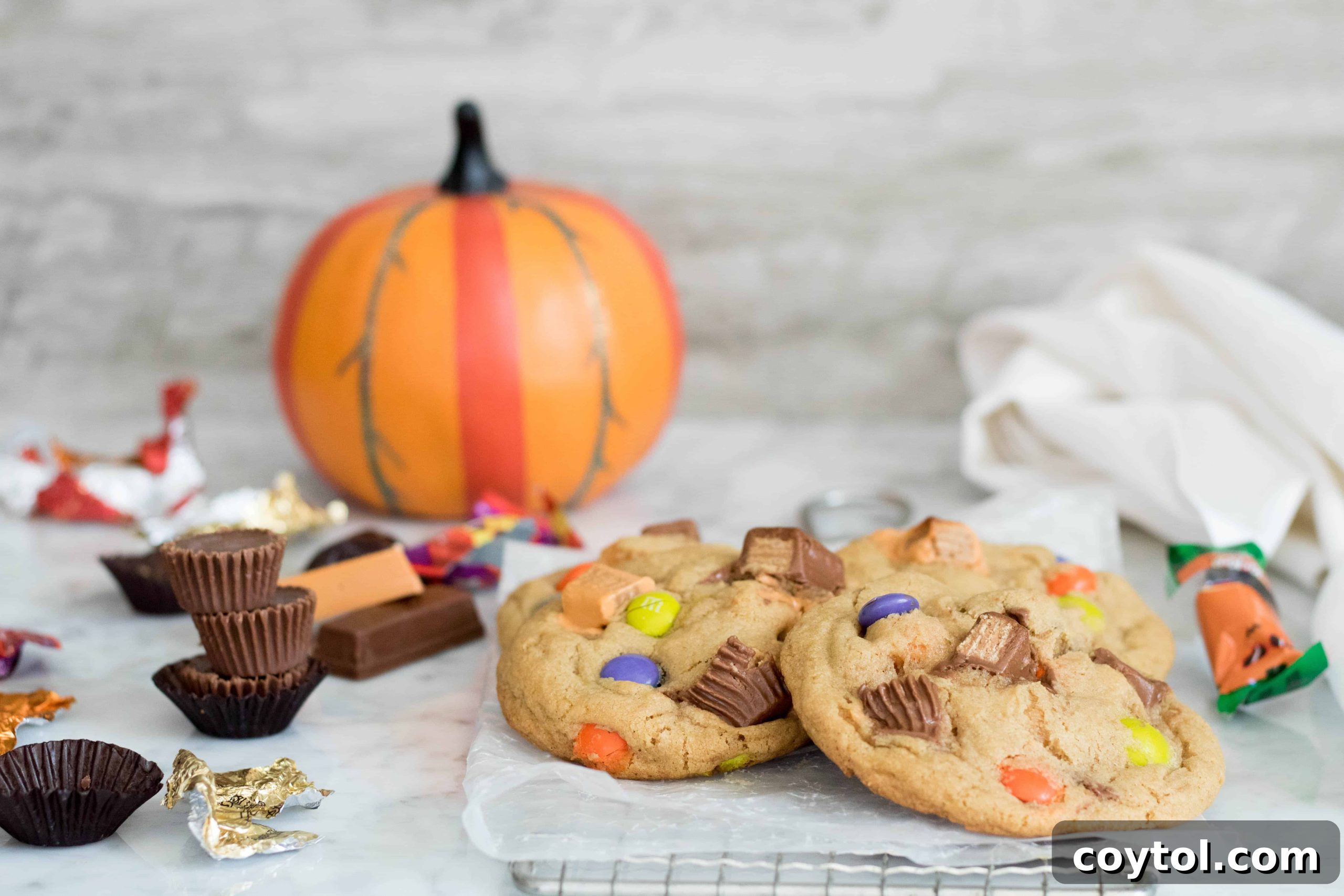 Two large, thick Halloween cookies generously packed with different leftover chocolates and candies, showcasing their delicious texture