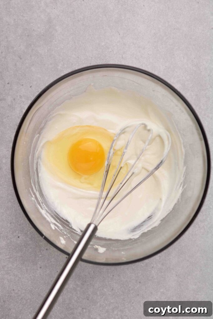 Step-by-step image 3: Whisking all wet ingredients until smooth and well combined for the cheesecake.