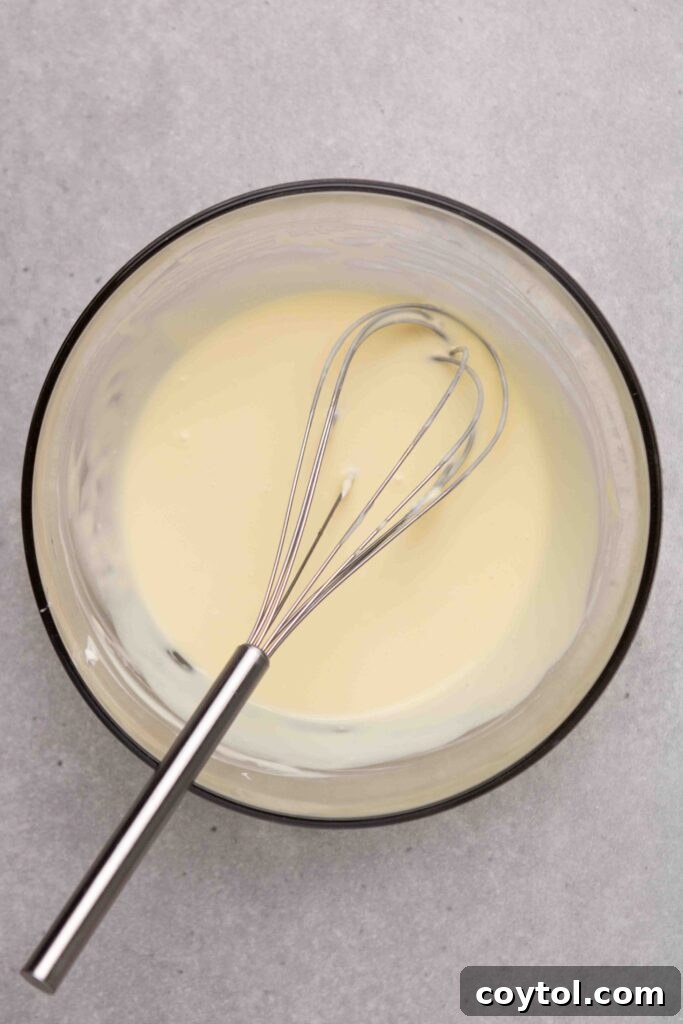 Step-by-step image 4: Gently incorporating flour into the cheesecake batter.