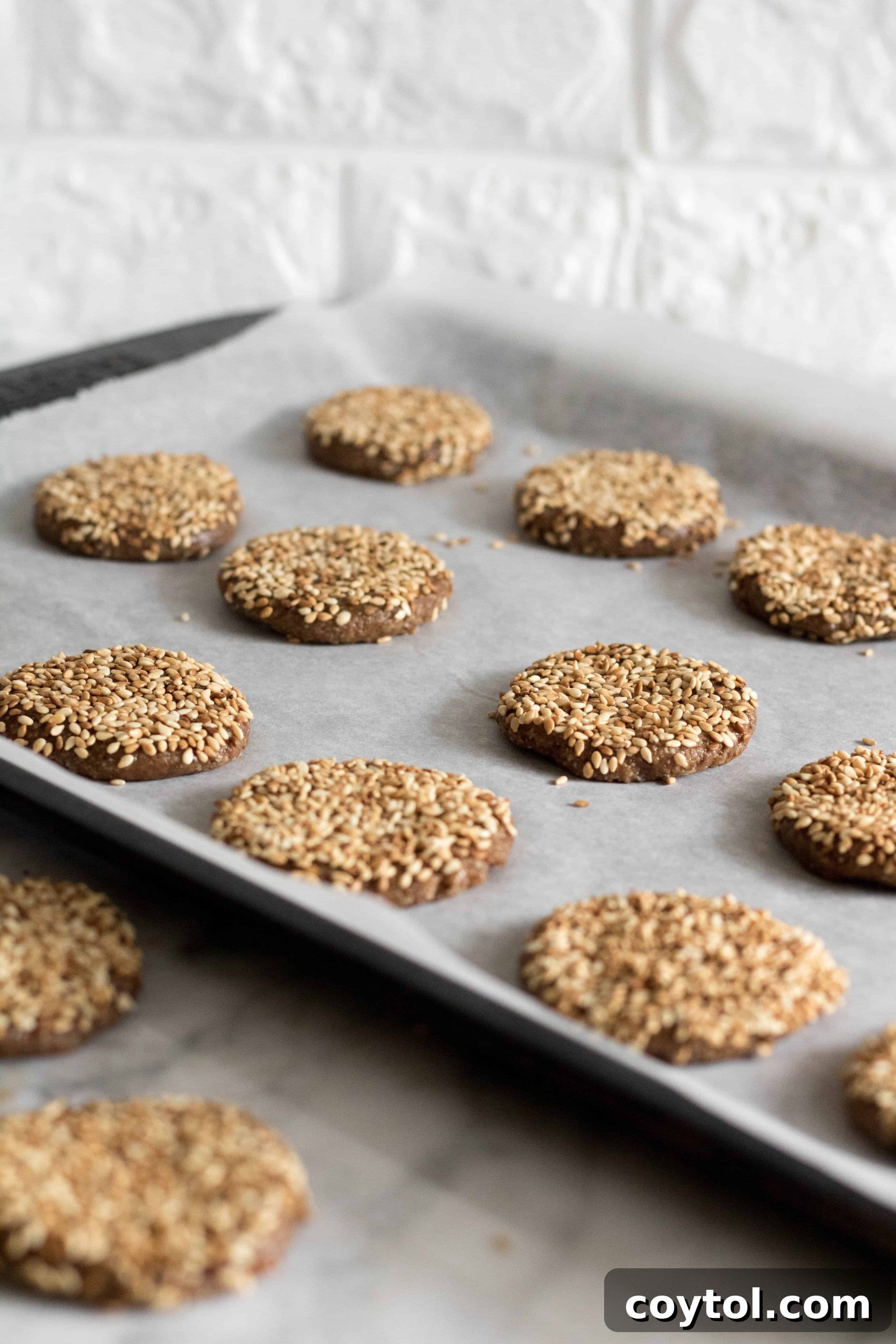 Tahini sesame seed cookies arranged on a baking sheet, spaced for optimal baking.