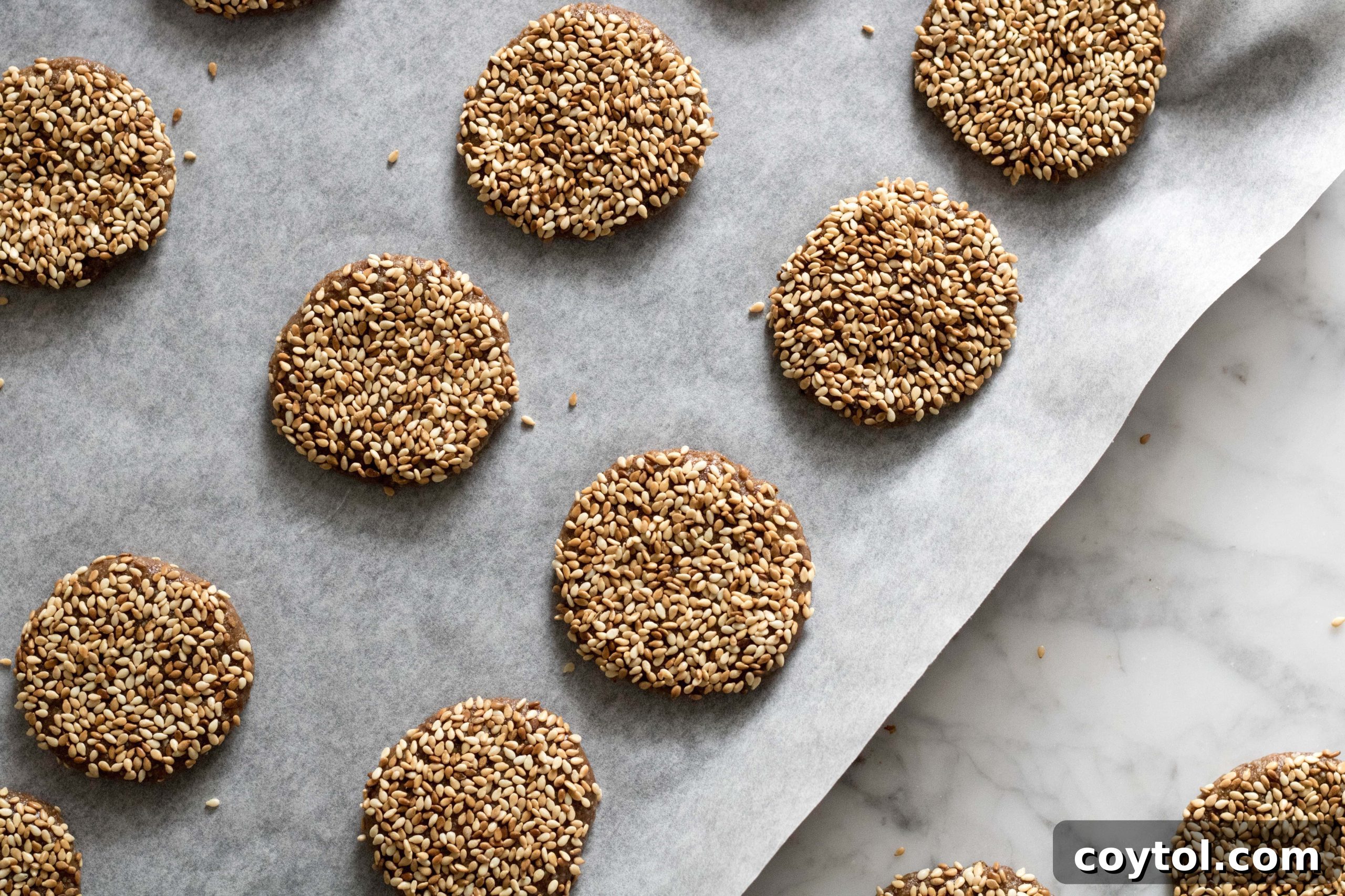 Close-up of healthy sesame cookies on parchment paper, showcasing sesame coating.