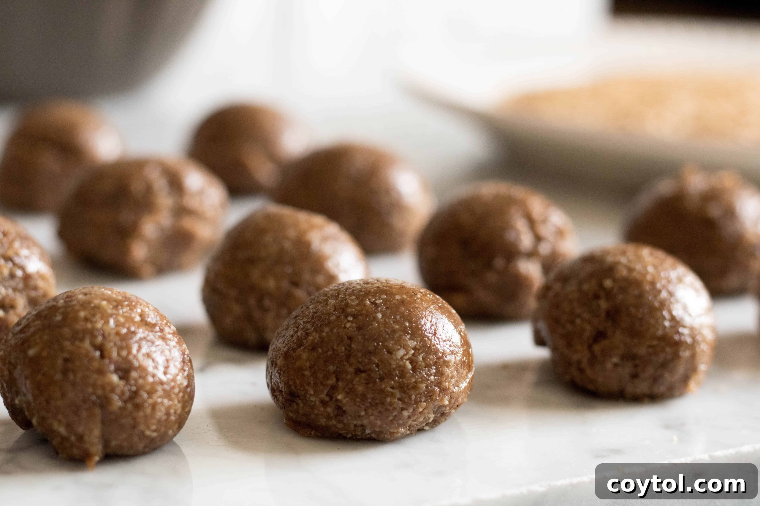 Scooping cookie dough for tahini sesame cookies with a measuring spoon.