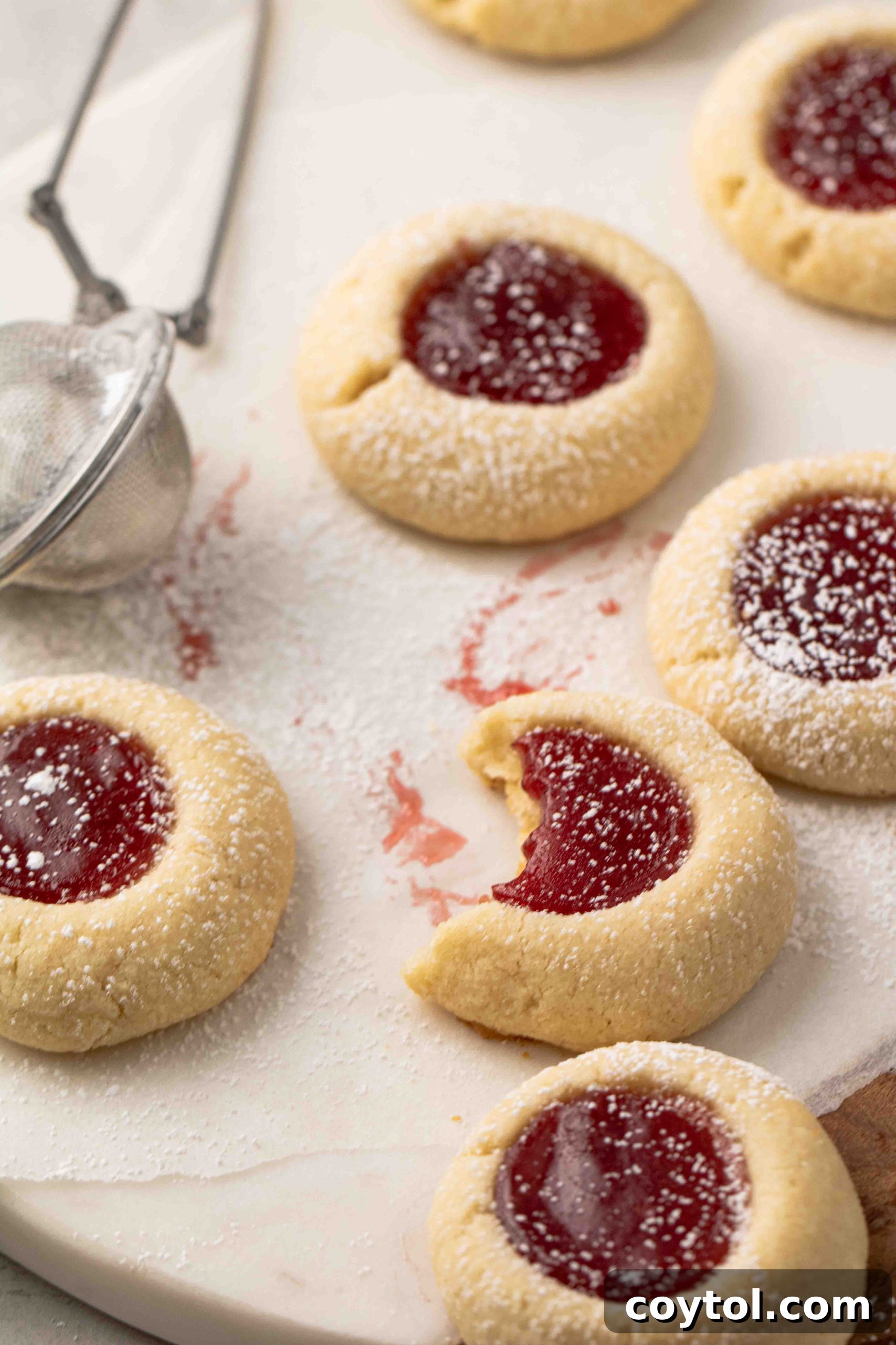 Easy raspberry thumbprint cookies displayed beautifully on a cooling rack, showing their golden edges and glistening red jam.