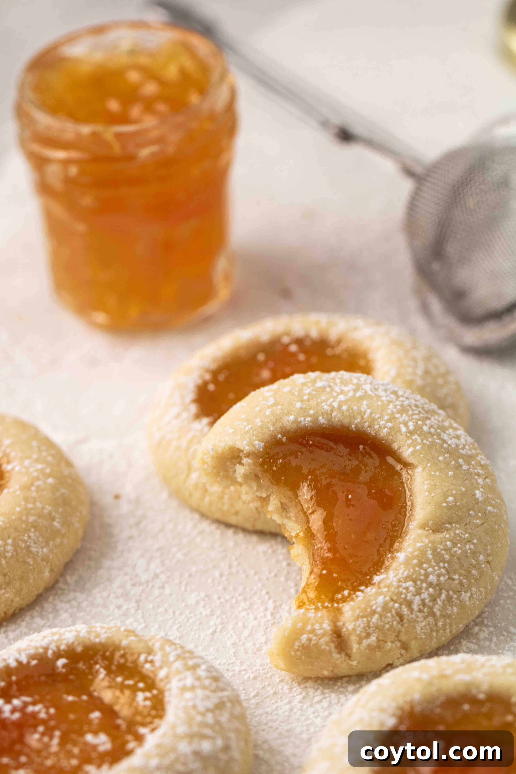 Close-up of golden apricot jam thumbprint cookies on a rustic wooden board, perfectly baked and ready to be served, highlighting their inviting appearance.