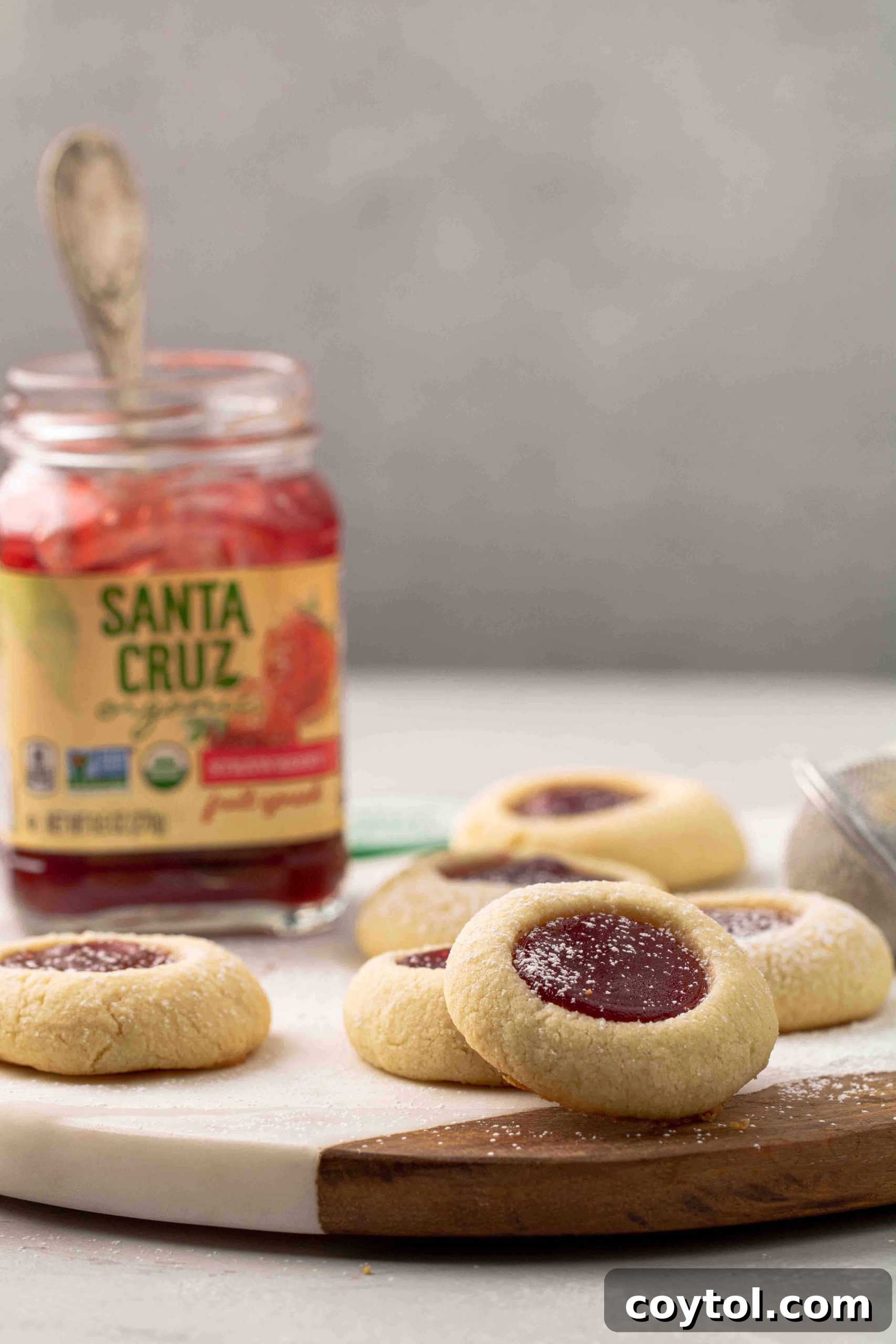 Straight-on shot of golden-brown thumbprint cookies arranged artfully on a white surface, showcasing their perfect rounded shape and inviting warmth.