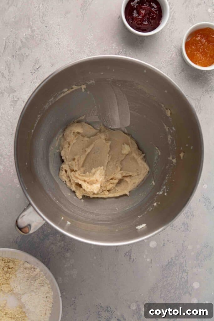 Step-by-step image: Creaming butter and sugar in a mixing bowl for thumbprint cookies until light and fluffy.