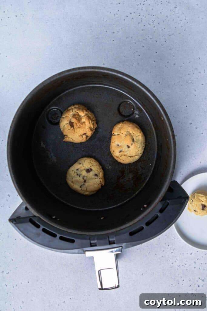 Perfectly baked chocolate chip cookies in the air fryer basket, golden brown and soft.