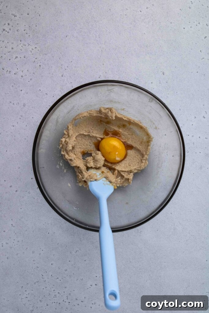 Adding a single egg yolk to the creamed butter and sugar mixture.