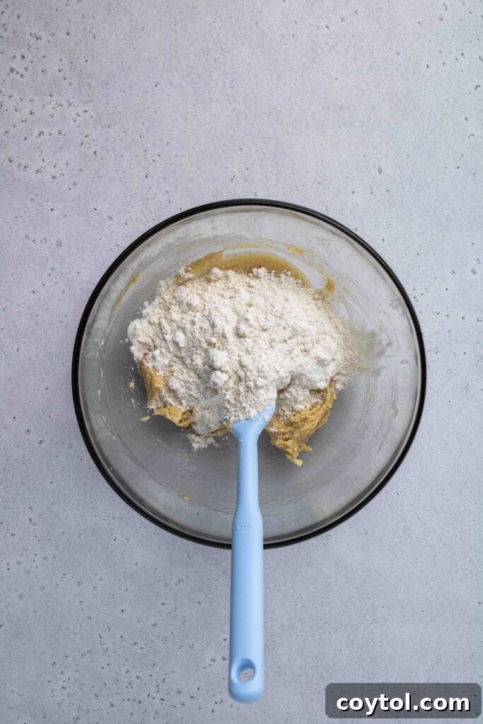 Incorporating all-purpose flour into the wet cookie dough mixture.