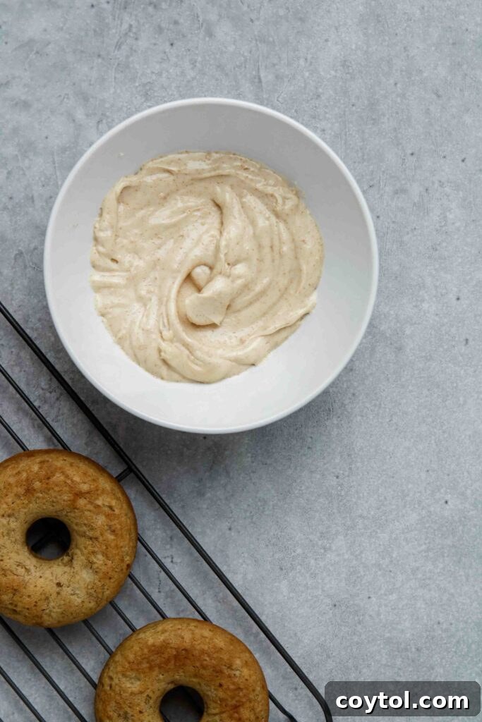 A baked banana donut being dipped into brown butter glaze.