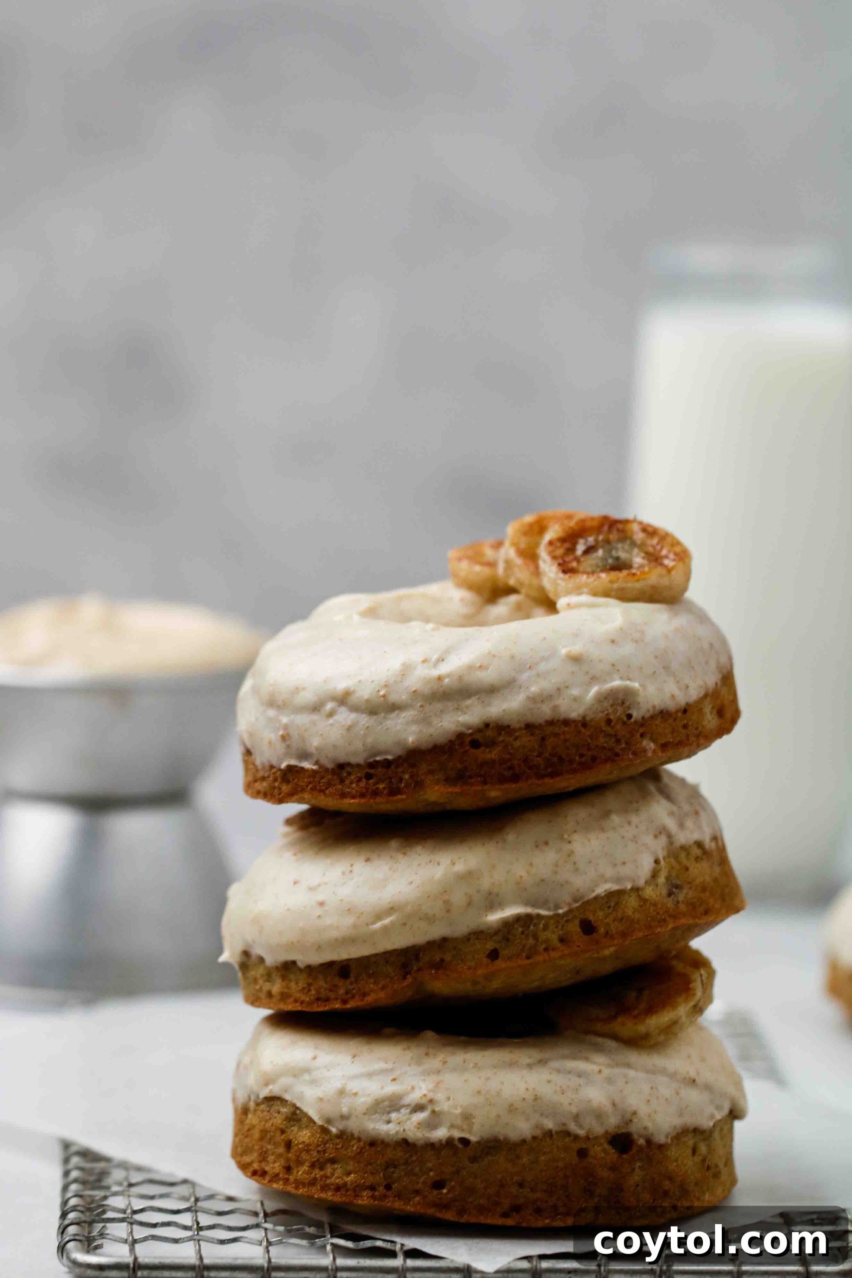A stack of several baked banana bread donuts, showing off their golden-brown exterior.