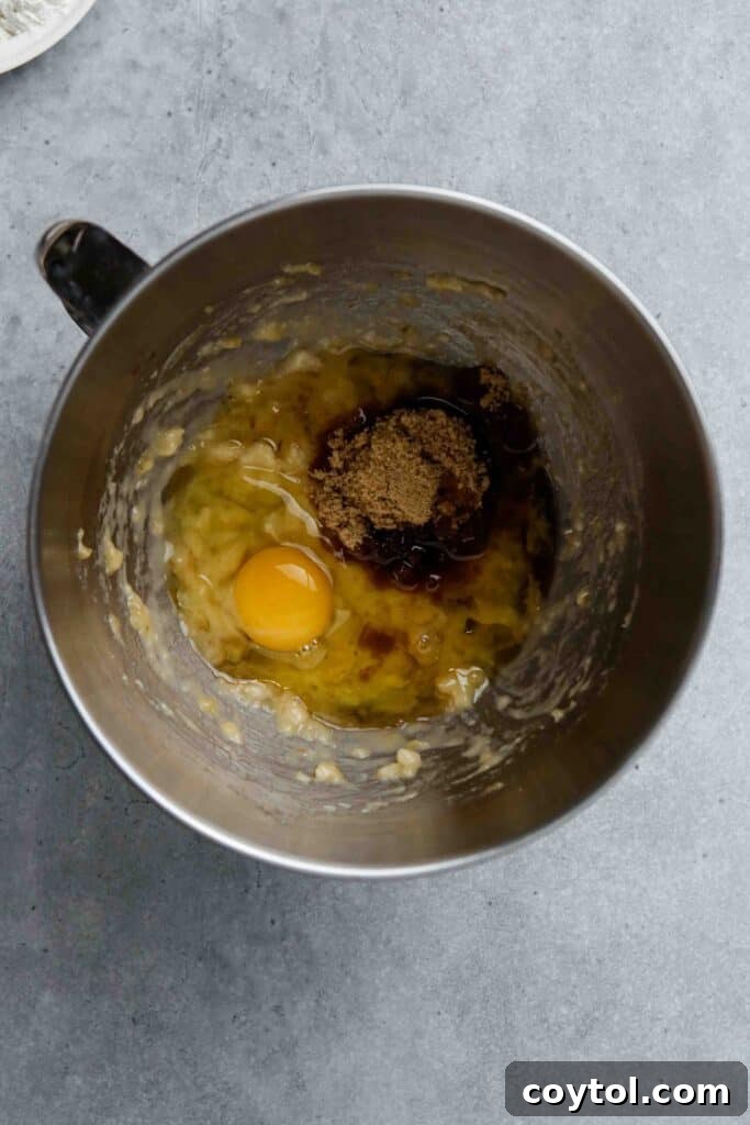 Mashed bananas being mixed with wet ingredients for banana donuts.