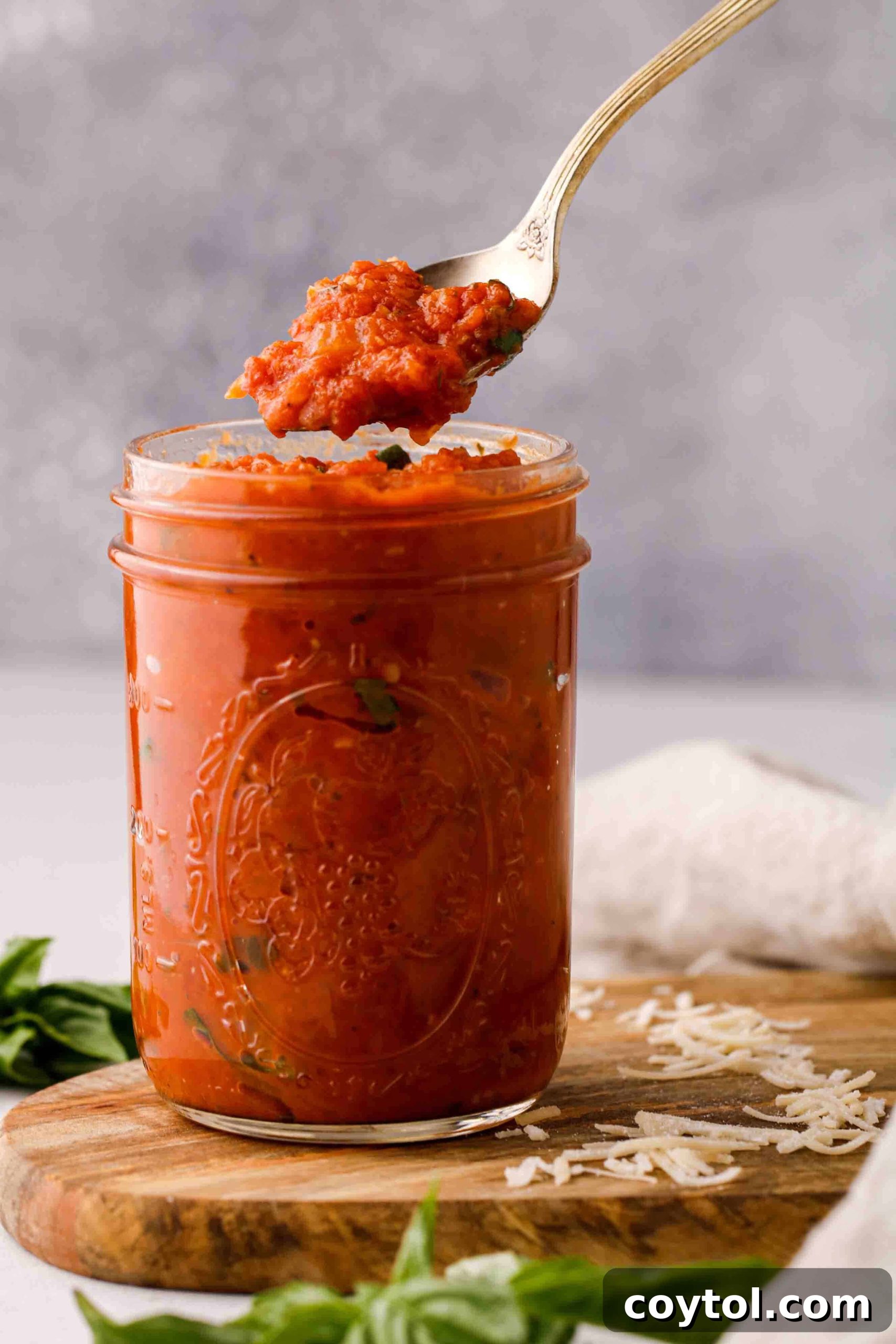 Speedy Homemade Marinara in 30 Minutes 11 A spoon lifting rich, thick homemade marinara sauce from a bowl, showcasing its texture.