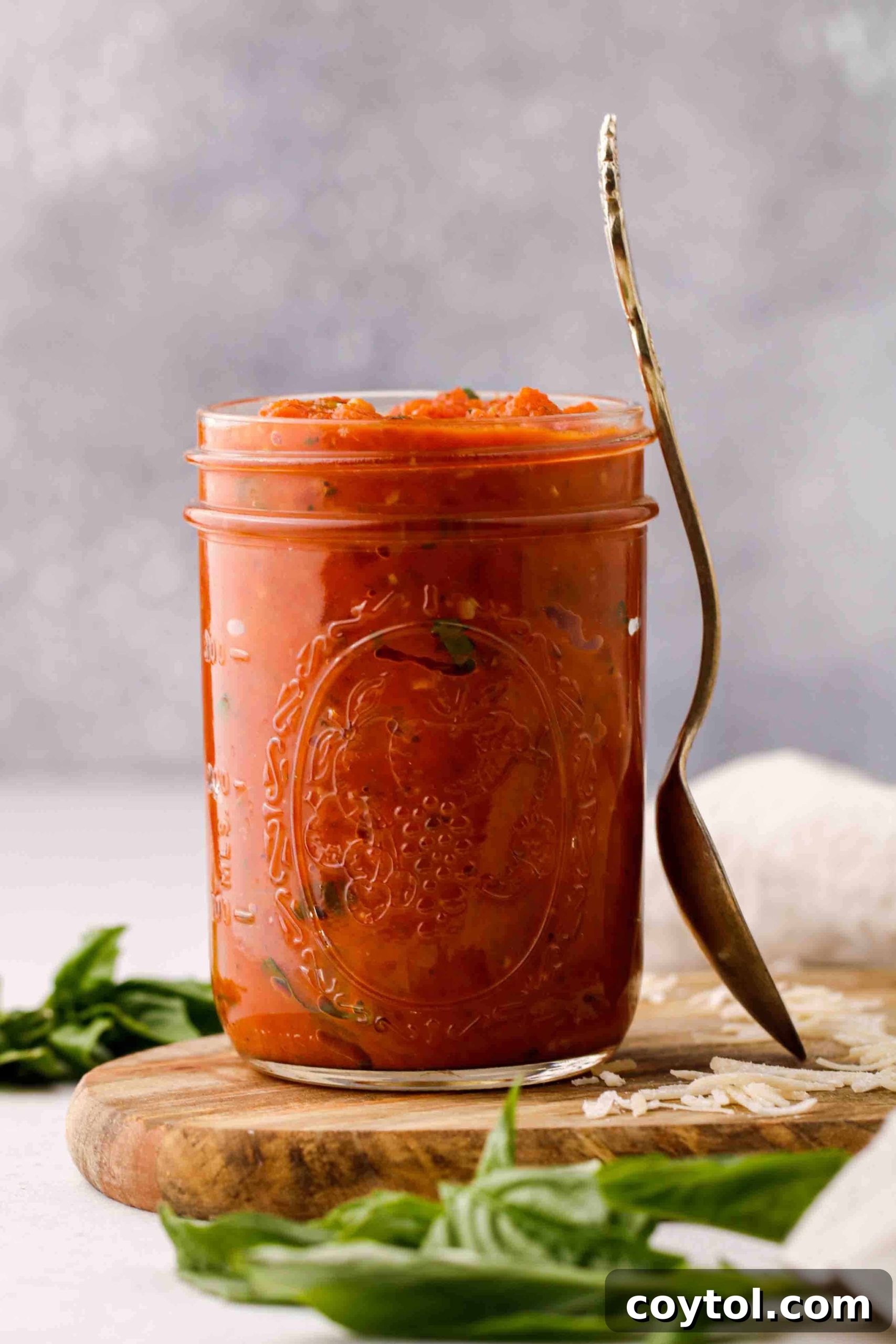 Speedy Homemade Marinara in 30 Minutes 5 Quick marinara sauce poured into a glass jar, garnished with a sprig of fresh basil.