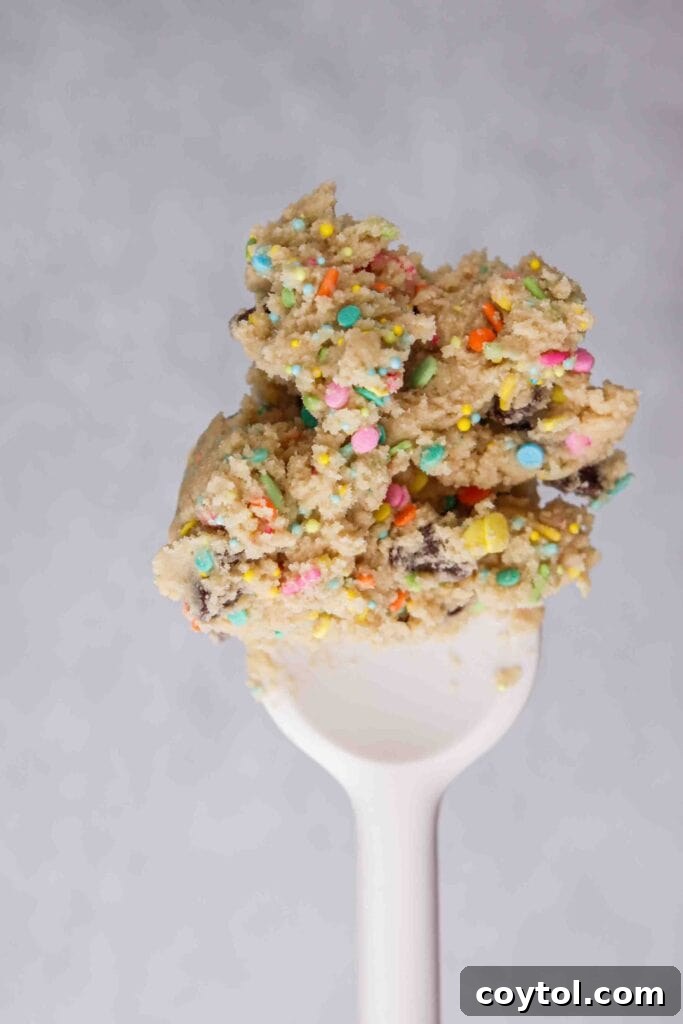 Close-up of chocolate chip cookie dough speckled generously with colorful sprinkles, ready for baking.