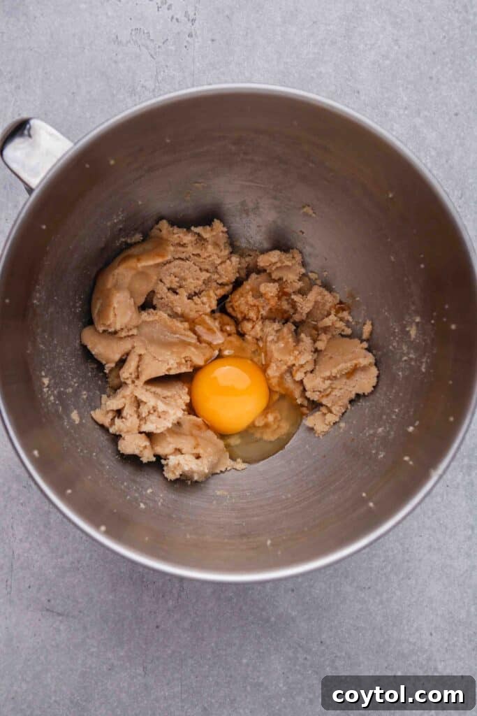 Adding an egg to the creamed butter and sugar mixture.